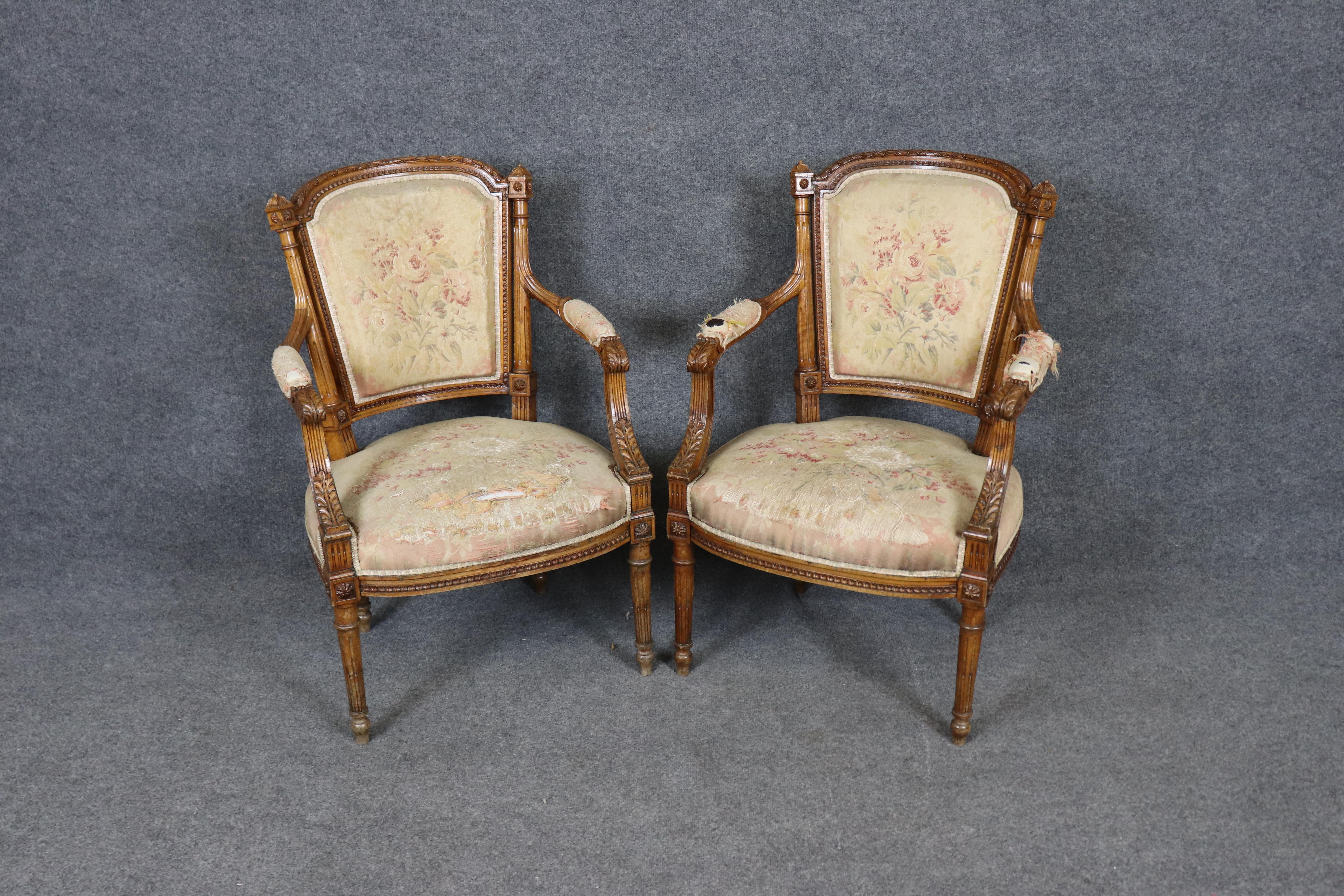 Esta exquisita pareja de sillones franceses Luis XVI, de finales del siglo XIX, capta maravillosamente la refinada elegancia del diseño neoclásico. Fabricadas con armazones de nogal finamente tallados, cada silla presenta patas estriadas, rosetones