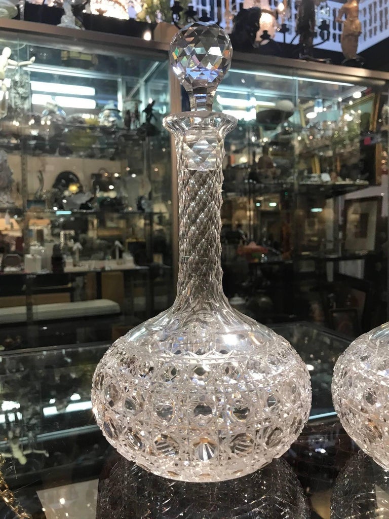 A shimmering pair of American handcut glass wine claret decanters with faceted stoppers. The bulbous bottoms with tall faceted necks and original ball facet stoppers. The body is in a Classic Russian cane pattern.