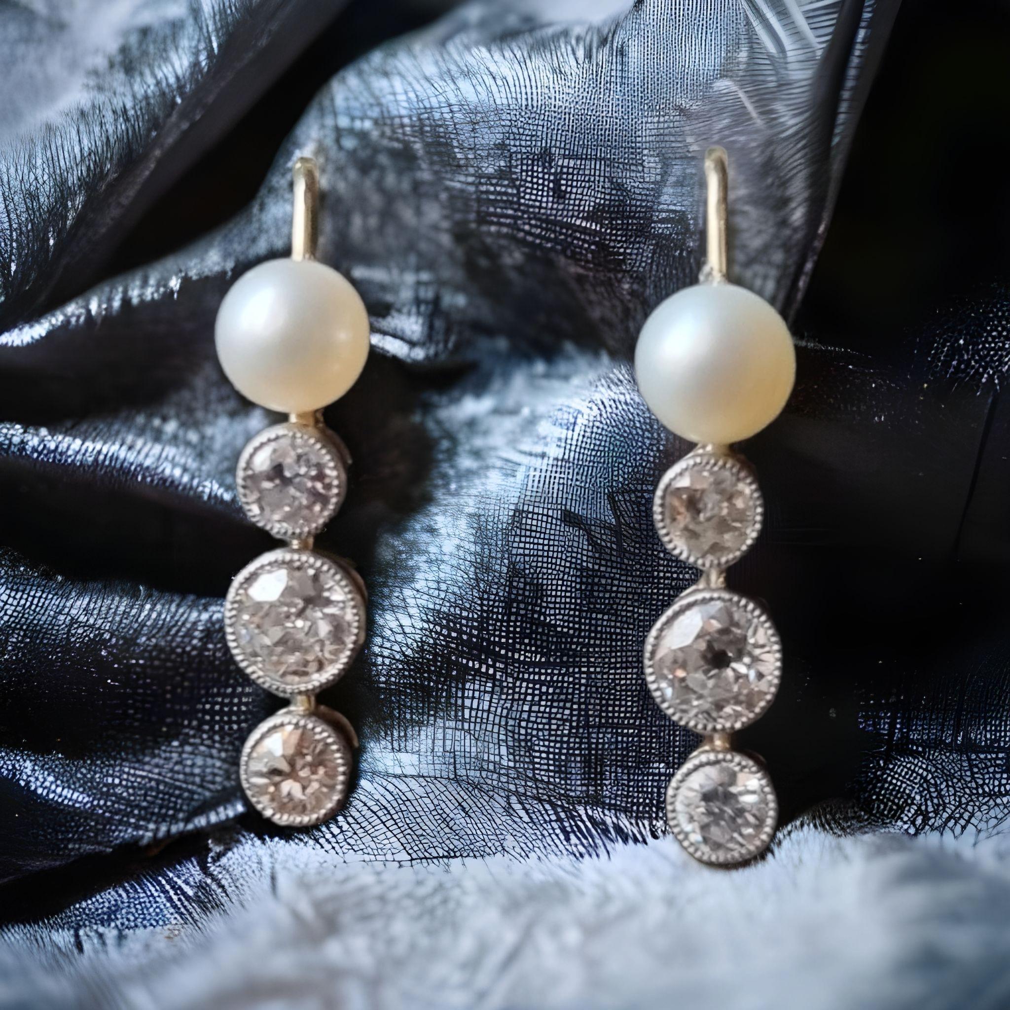 A PAIR OF LATE 19TH CENTURY PEARL AND DIAMOND PENDENT EARRINGS
From  the top of each pearl suspending vertically set from three graduated old brilliant-cut diamonds suspending, approx. weighing 0.60 cts, pearls untested diameter 5mm, with gold hook