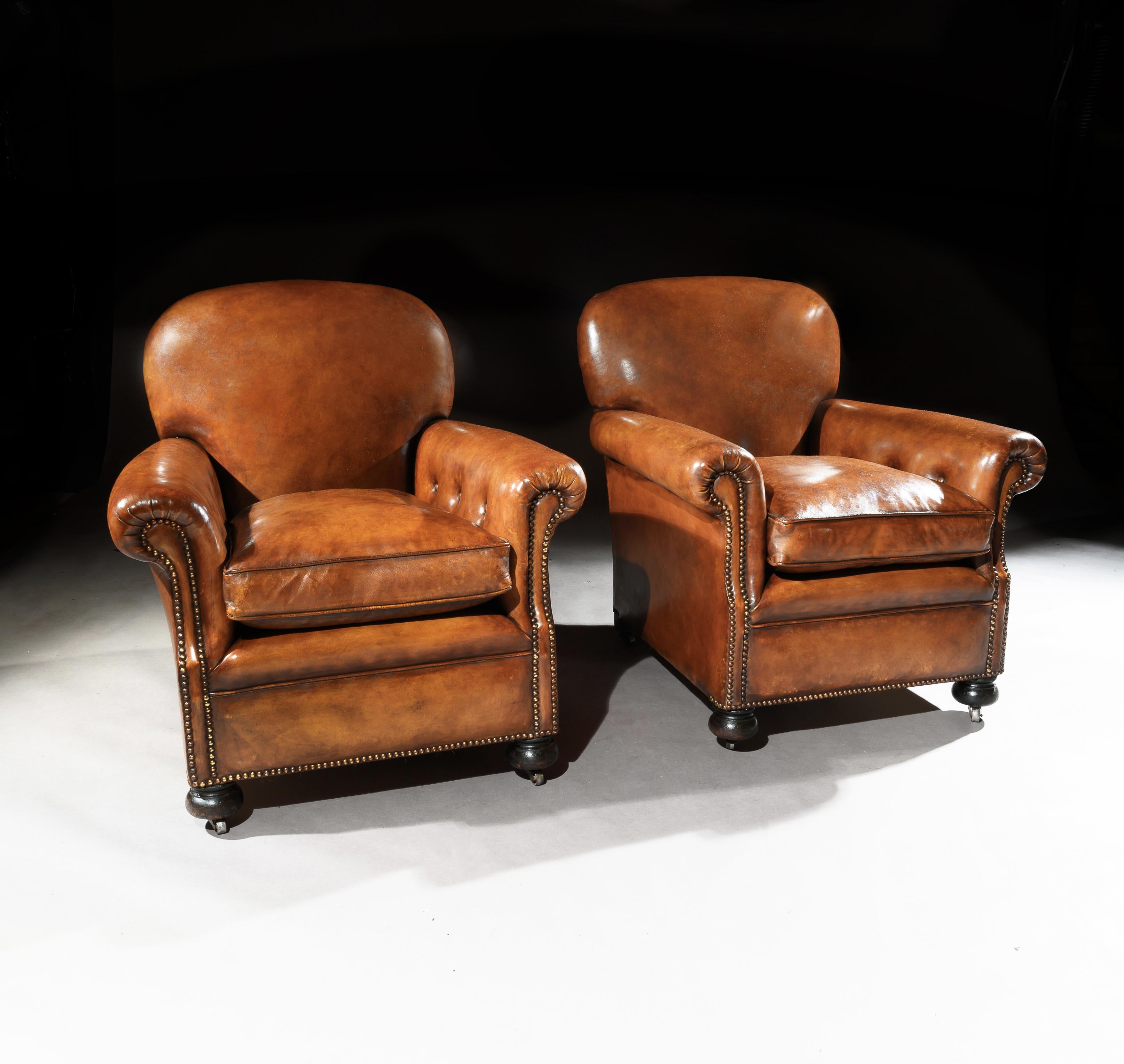 A fine pair of antique leather club chairs raised on turned front bun feet, of very good proportions and extremely comfortable.

English, circa 1900s

This pair of club chairs date from the early 20th century, having a doomed shaped back with