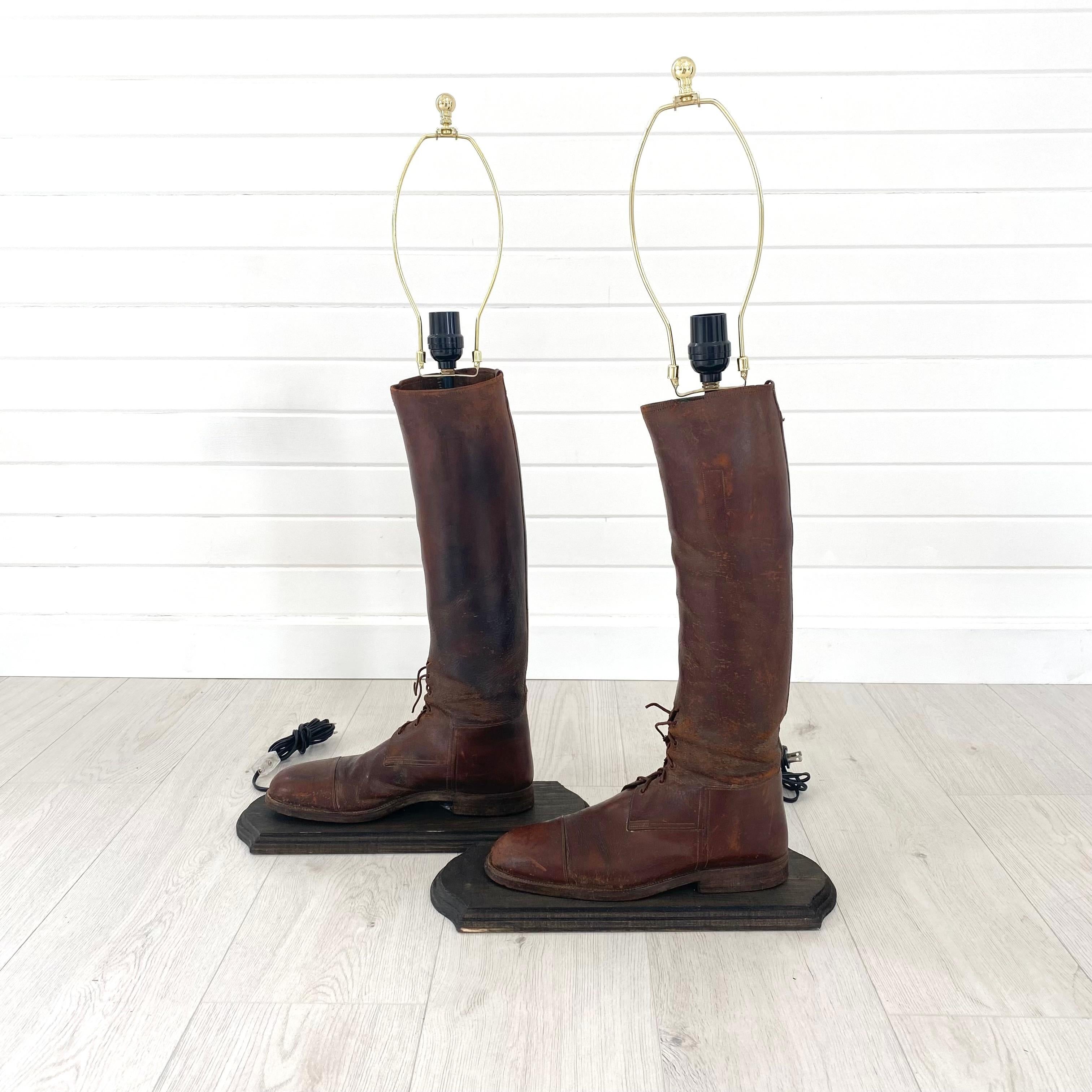 Incroyable paire unique de lampes vintage fabriquées à partir de bottes d'équitation anglaises anciennes montées. Le cuir centenaire est altéré et patiné. Les plaques sont en bois foncé et teinté. Quincaillerie en laiton et feutre vert moulé à