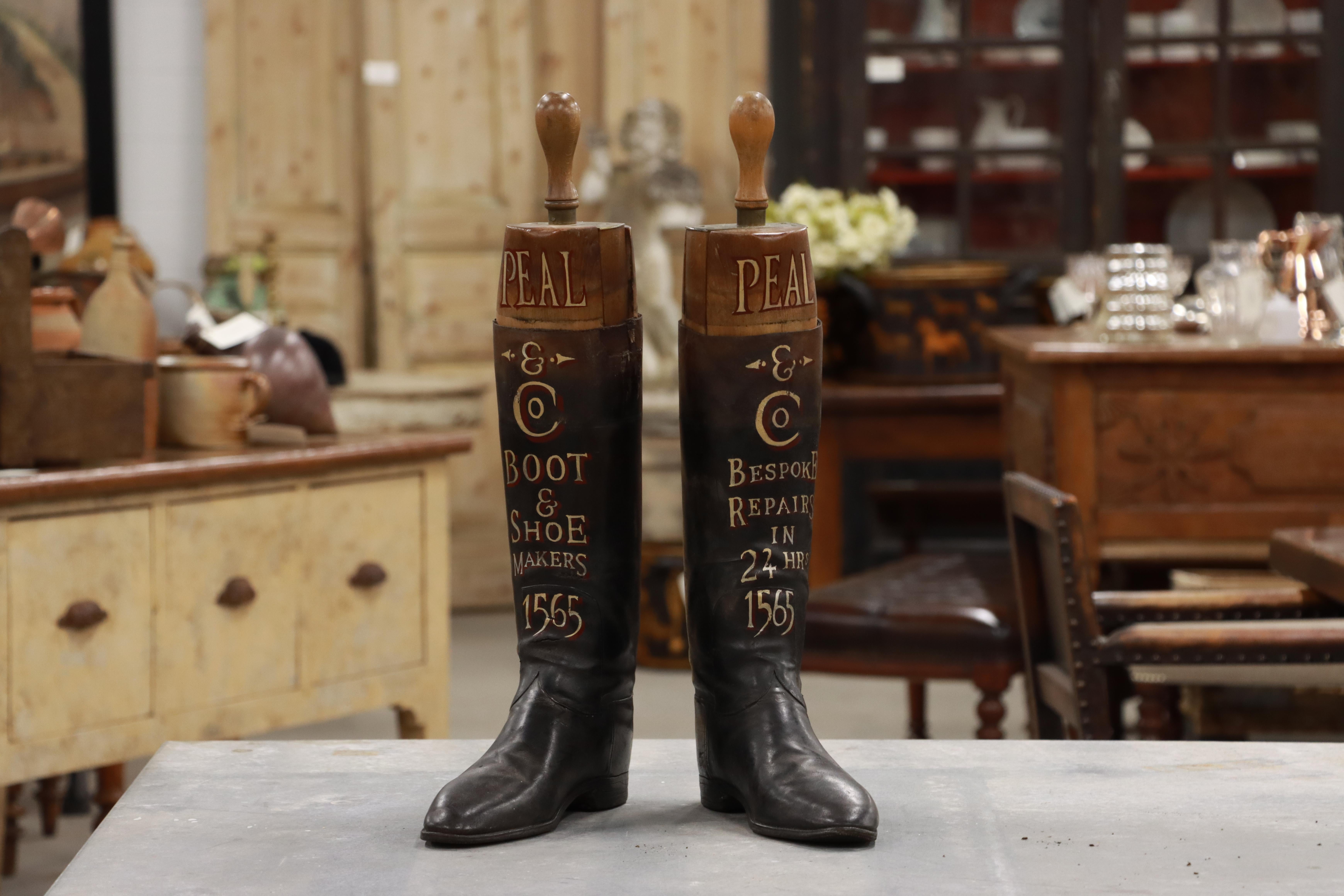 Paire de bottes d'équitation anglaises anciennes en cuir avec leurs arbres d'origine en bois dur. Les deux bottes sont décorées d'un lettrage doré, annonçant Peal & Co. (appliqué plus tard). 

Peal a fabriqué des chaussures et des bottes à Londres