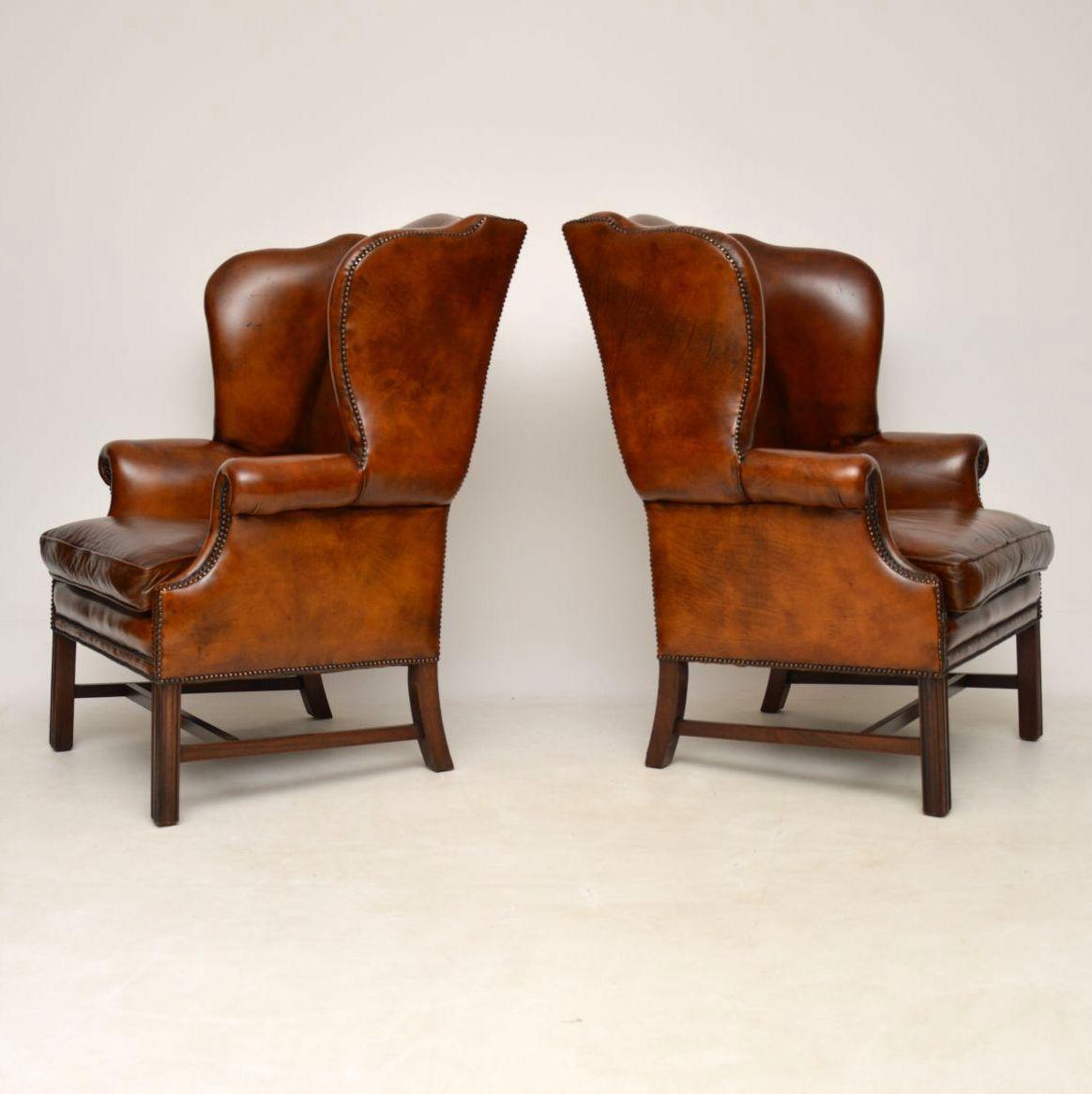 This very impressive large pair of antique leather & mahogany wing armchairs have very generous proportions & are extremely comfortable. They also have a lovely naturally aged colour to the original leather & there are no rips, tears or holes. This