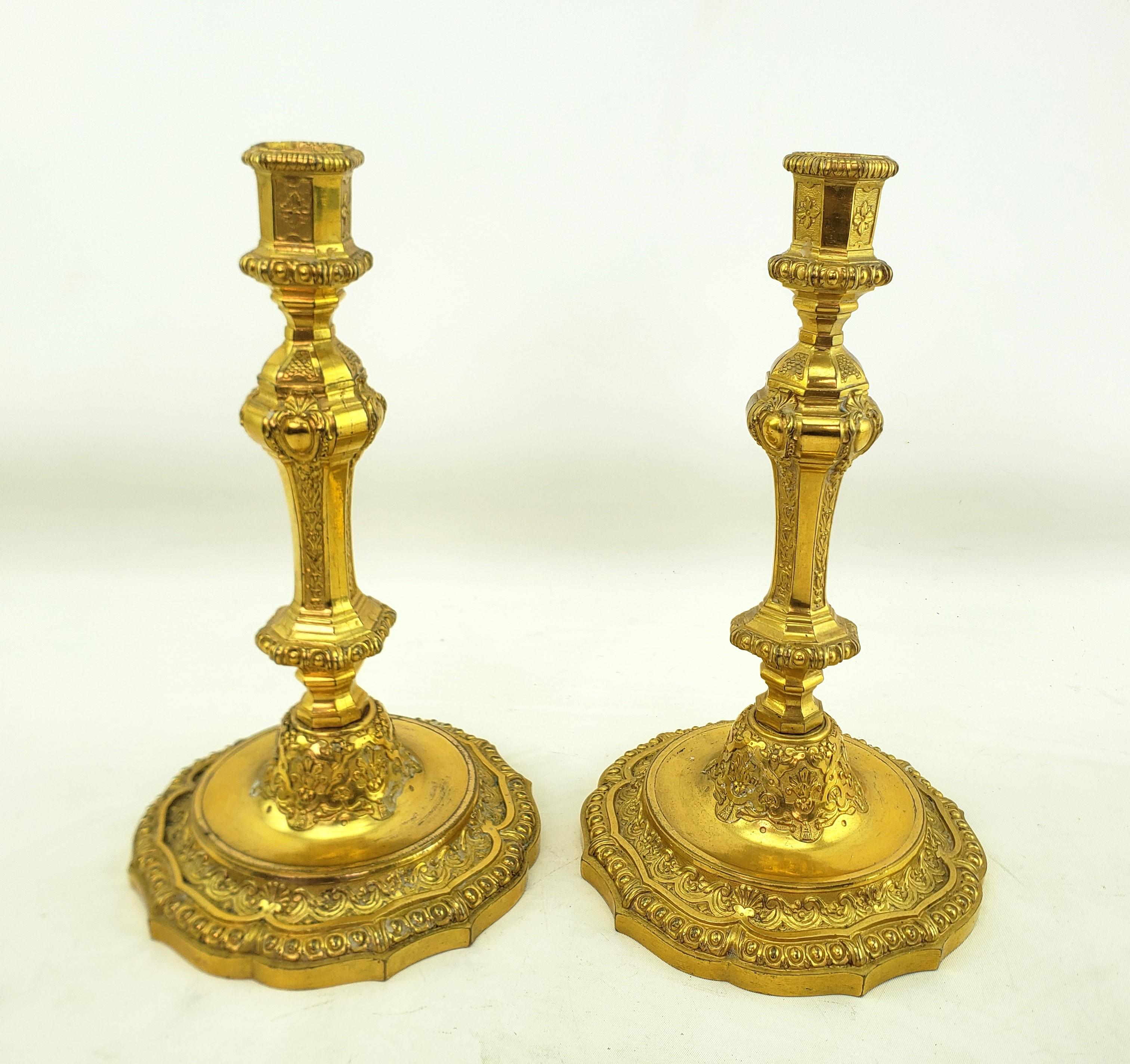 This pair of antique candlesticks are unsigned, but presumed to have originated from France and date to approximately 1880 and done in a Louis XIV style. The candlesticks are composed of ornately cast bronze with decorative stylized flowers and