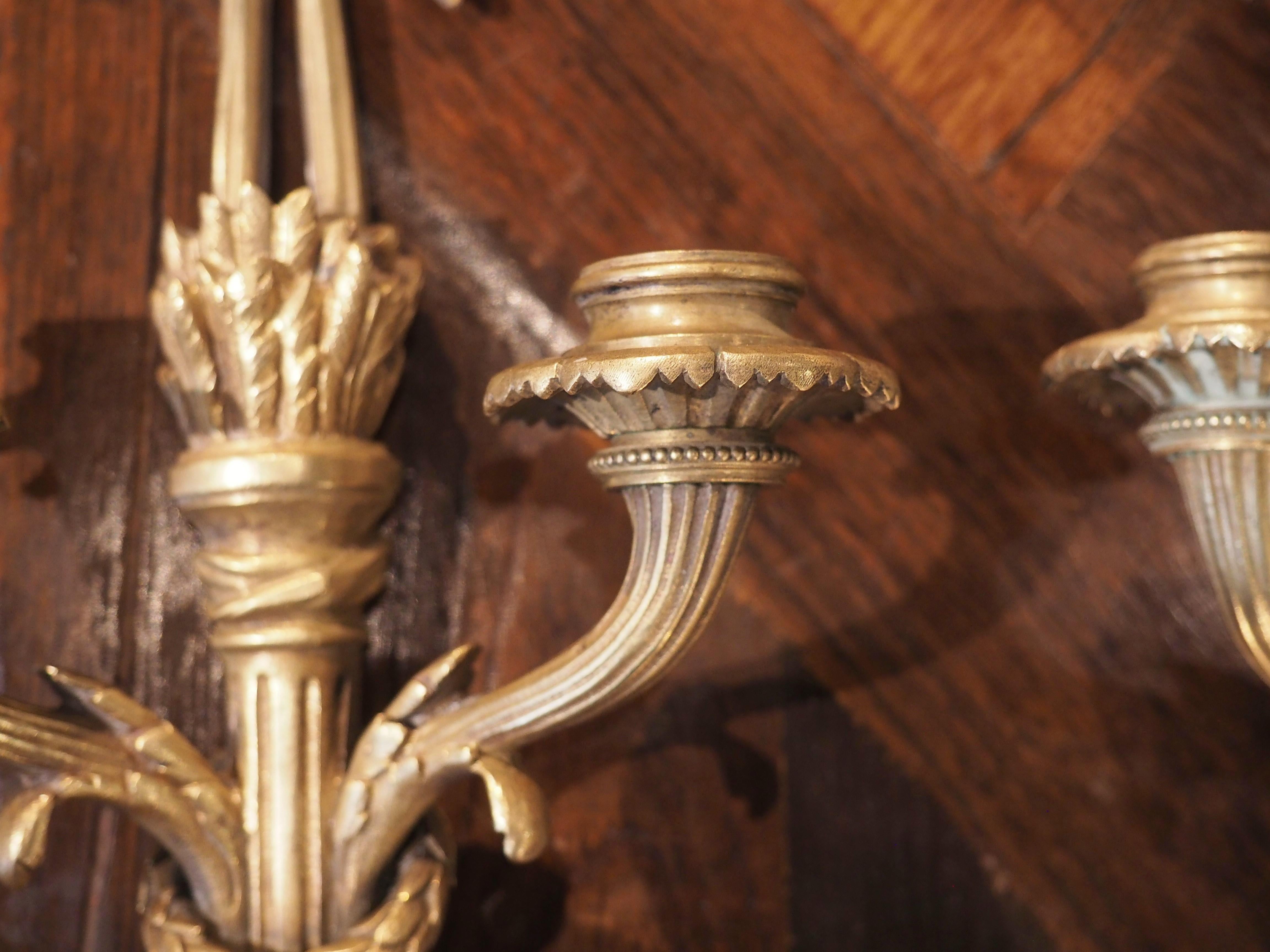 Neoclassical motifs were an important part of the Louis XVI period, reflecting the rediscovery of the lost ancient Roman cities, Herculaneum and Pompeii, in the middle 18th century. Our pair of bronze dore sconces from France were cast in the style
