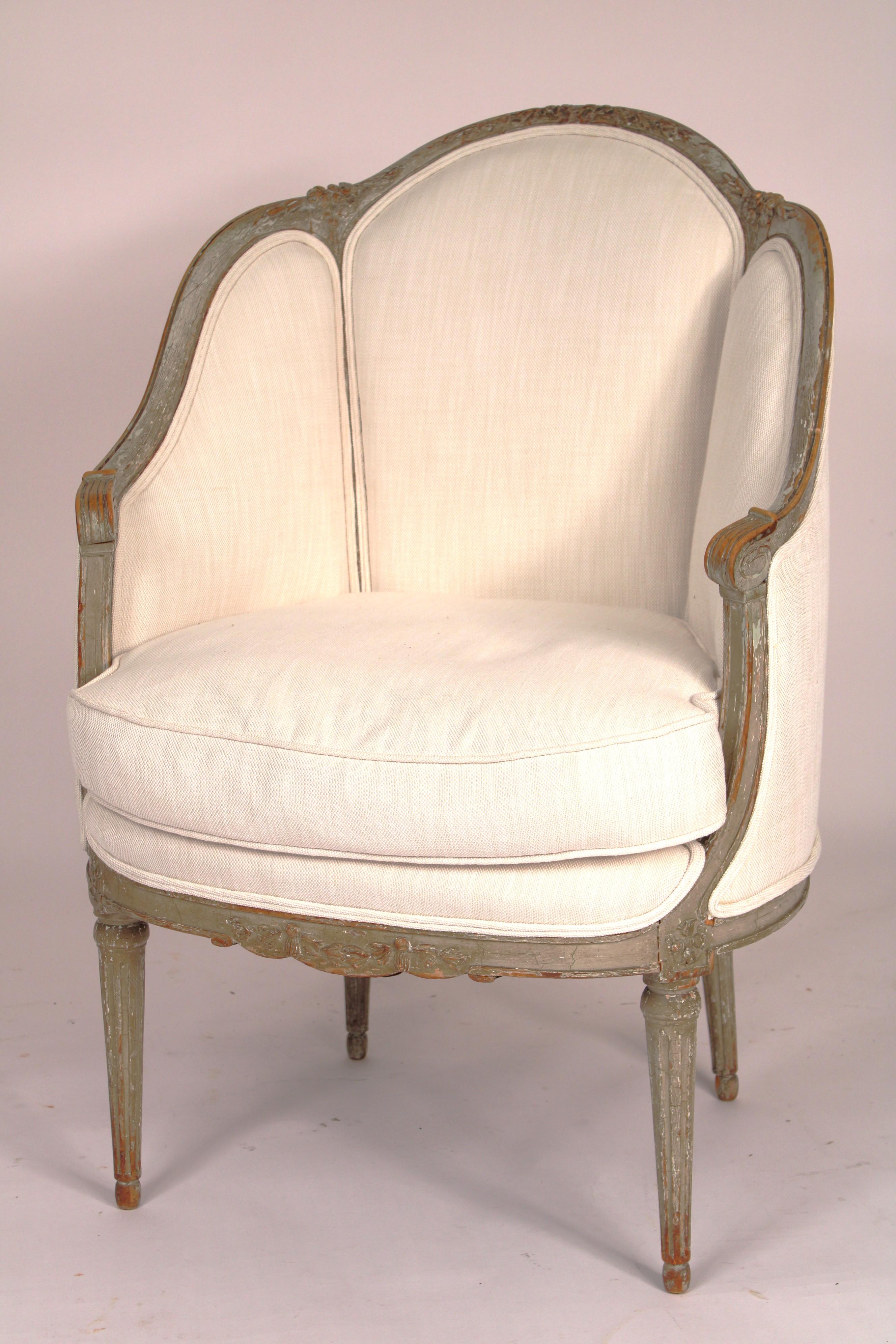 Pair of antique Louis XVI style grisaille painted bergeres, 19th century. With original grisaille paint. Arched back with floral carving, serpentine shaped down swept arms, resting on turned fluted tapered legs. Recently reupholstered, upholstery is