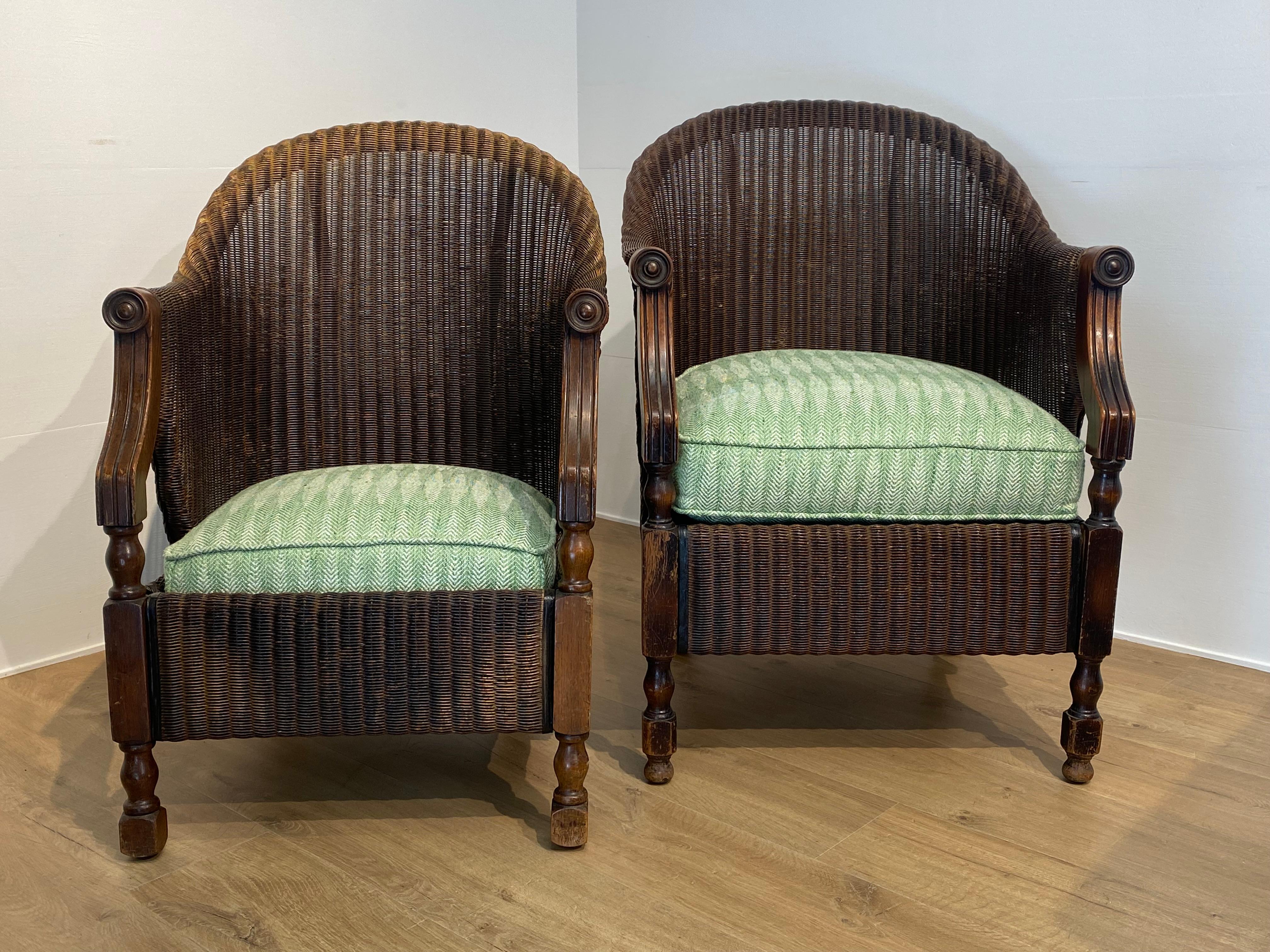 Elegant Pair of  Loyd Loom Club Chairs,
in a basic Brown - Natural Color, the pair consists of a Male and a smaller Female model, good and warm patina of the polish d rattan,
the seats are newly upholstered with the Spanish Fabric of Gaston Y 