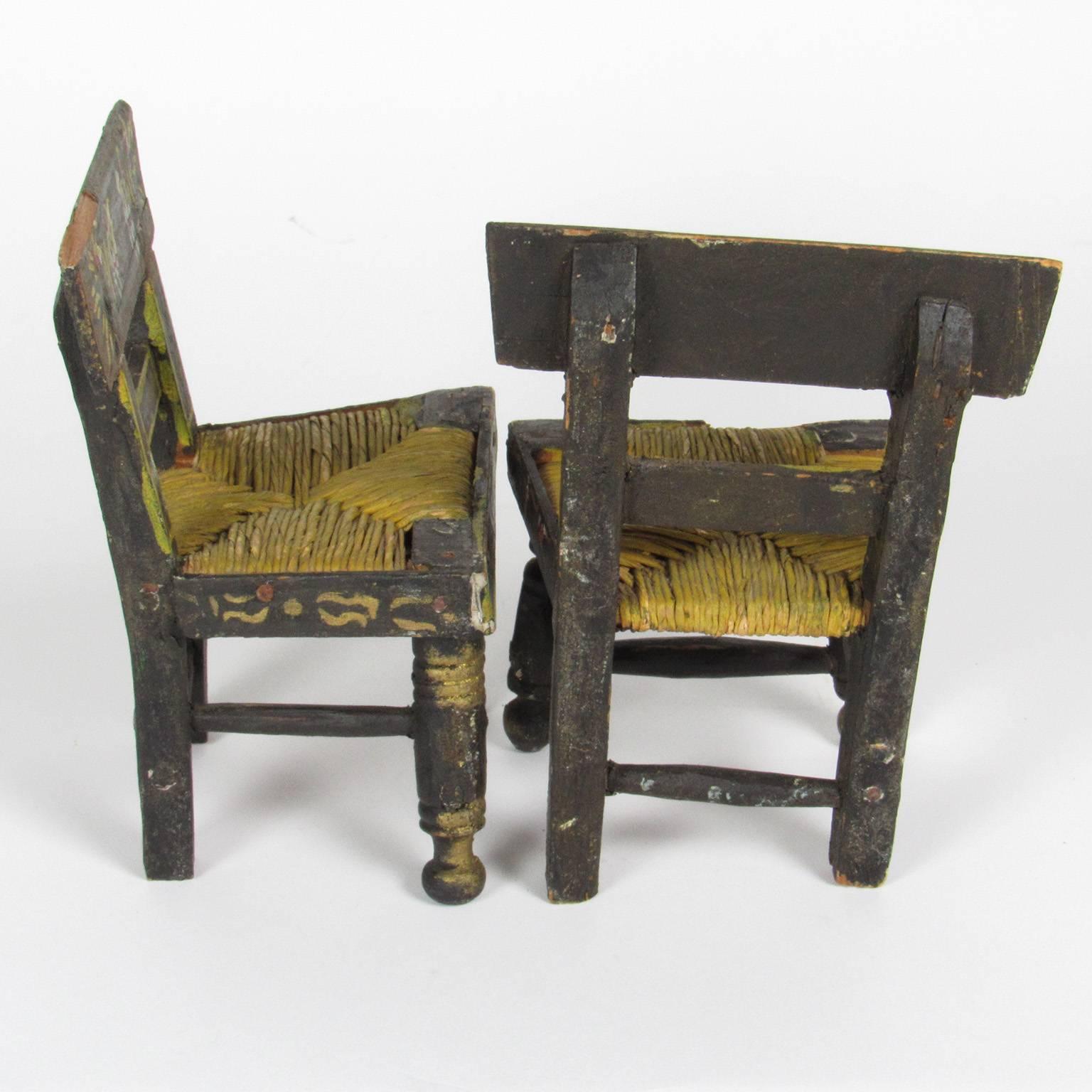 Pair of antique miniature hand-painted Hitchcock style chairs. Black painted with rush seats, these miniature chairs are adorable! Dimensions: 5 3/4 x 3 3/4 x 3 inches.