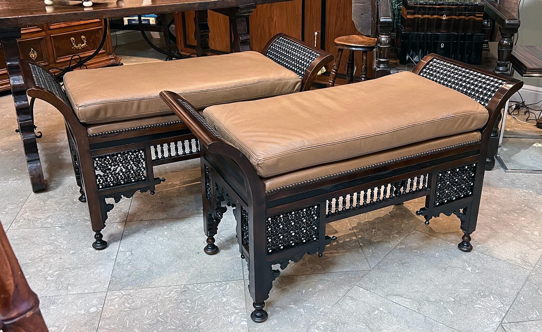 The semi-attached leather cushion flanked by dramatic flared openwork arms with intricate inlay over a similar openwork apron and turned elements creating an elaborate latticework; with beautifully carved spandrels above turned feet; the benches