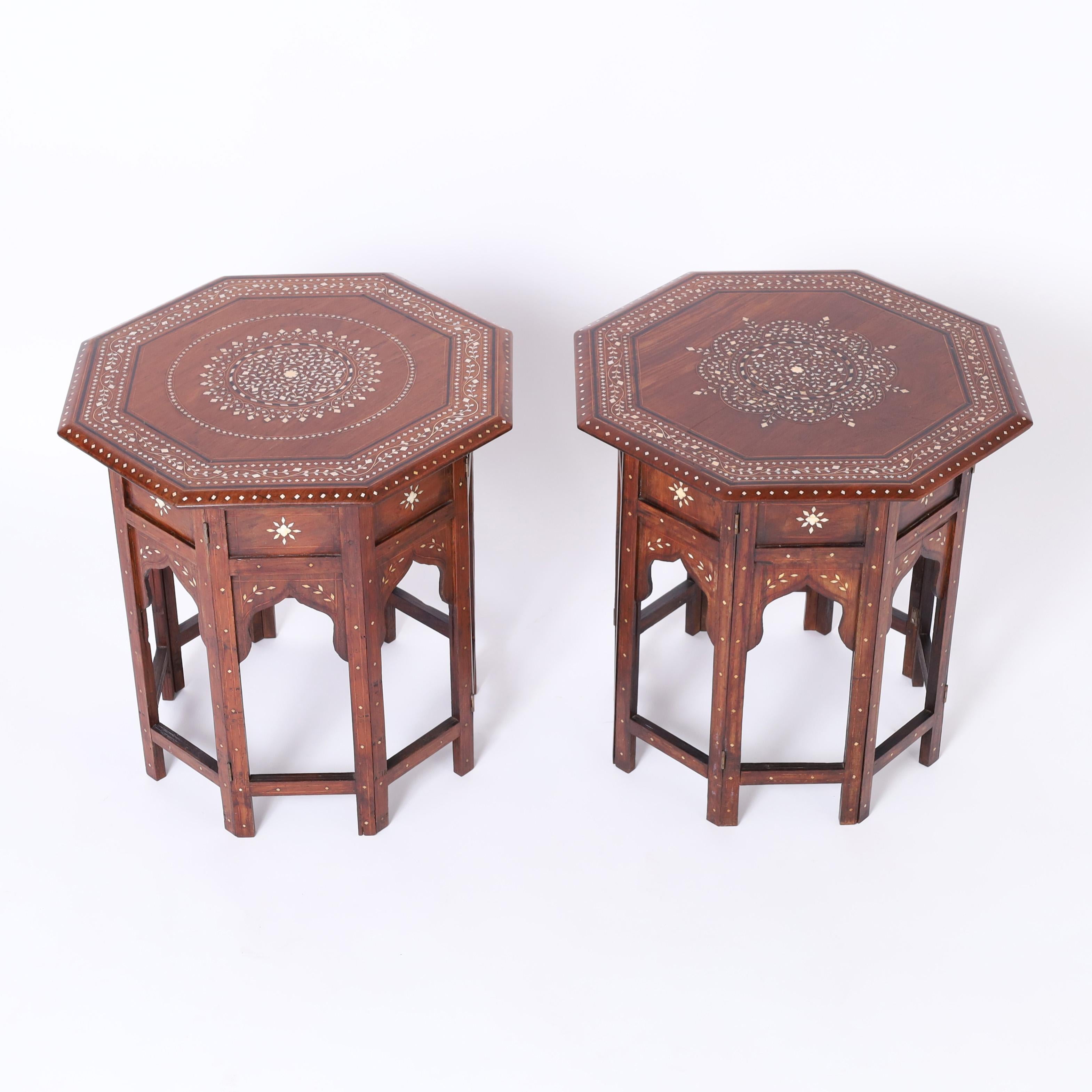 Intriguing pair of Moroccan stands crafted in mahogany having octagon tops inlaid with bone in floral patterns highlighted in ebony and kingwood on eight sided bases with bone inlays and moorish arches. 