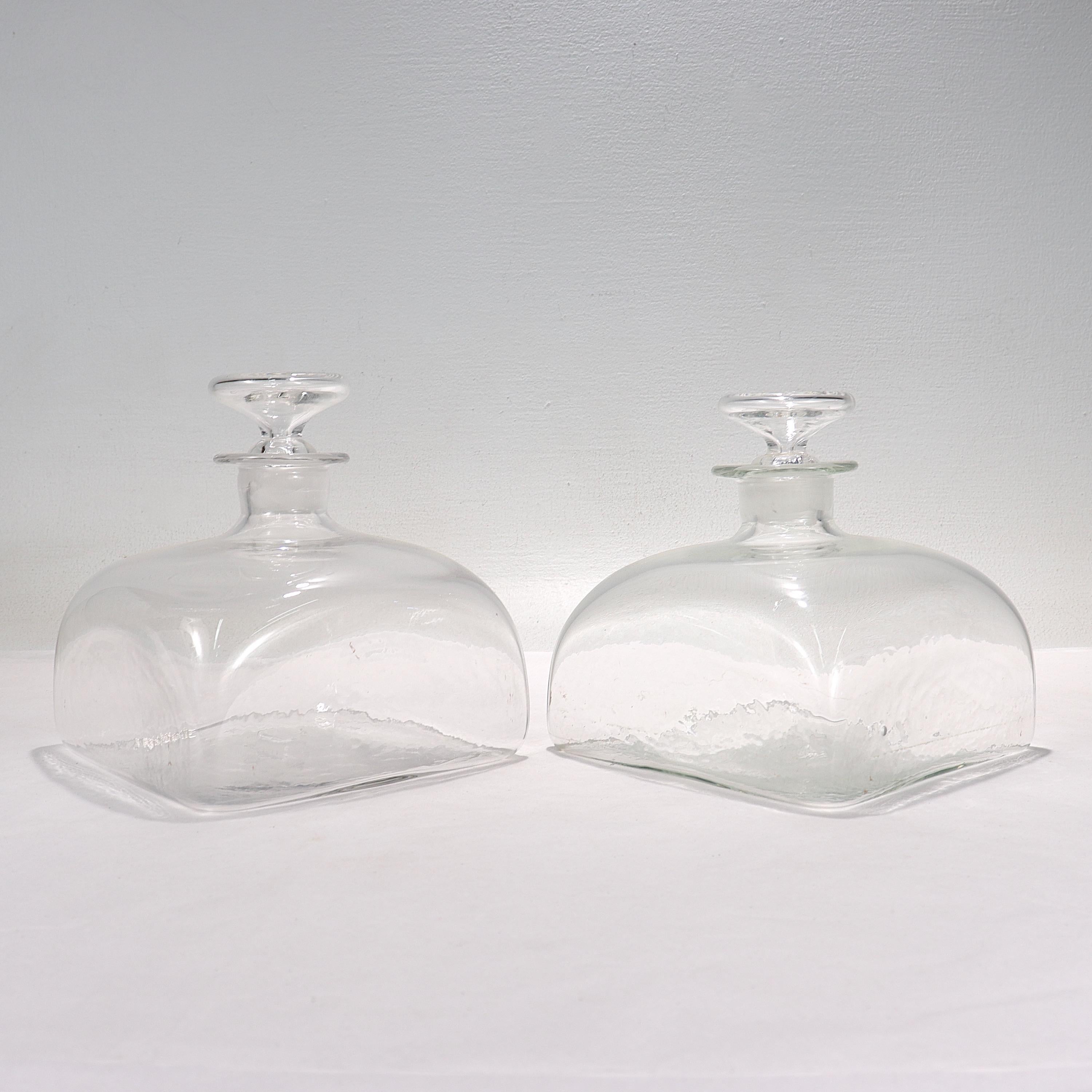 A fine pair of antique glass ship decanters.

Each with a square base and stoppers with circular knob handles.

Each has a polished pontil mark to the base.

Simply a great pair of glass decanters!

Date:
early 20th century or