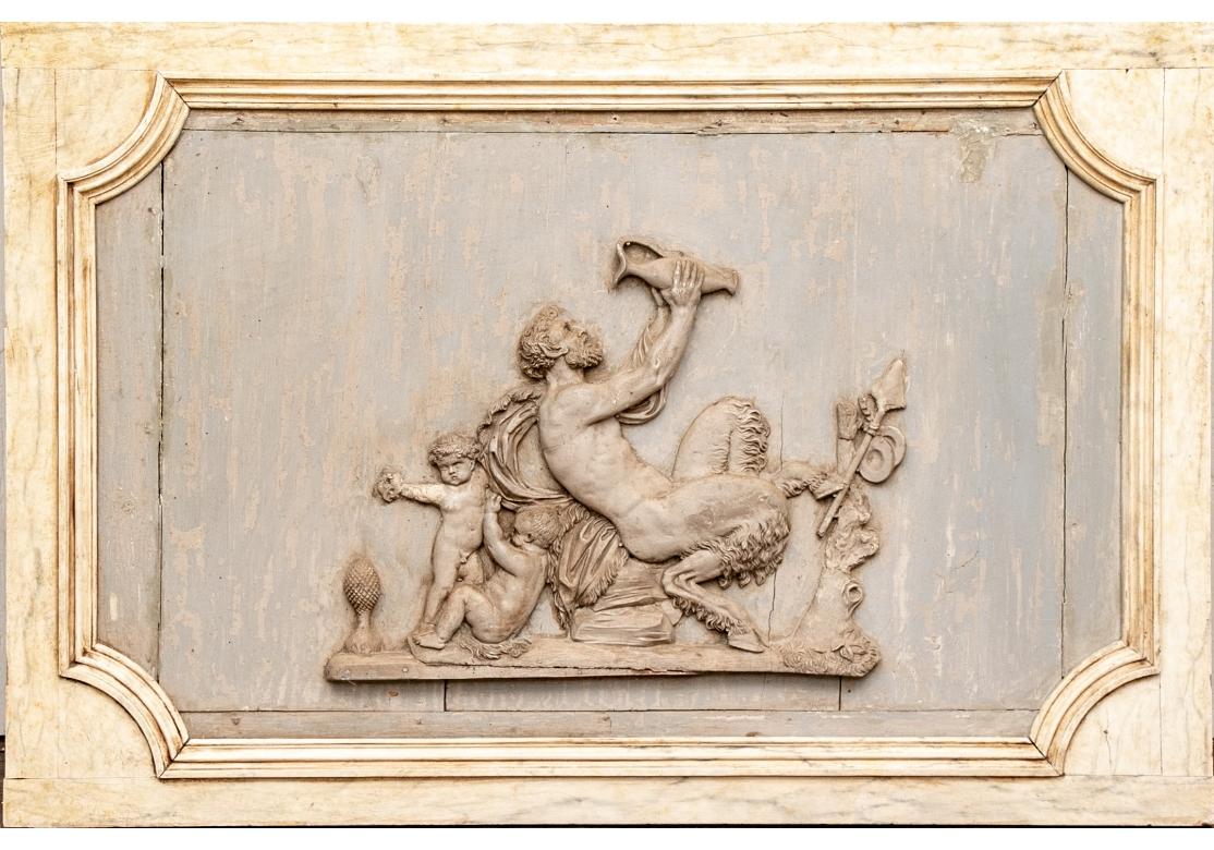 Rare, extraordinaire et précoce paire de plaques néoclassiques. L'une d'elles présente une plaque en relief sculptée et peinte de style bacchique avec des putti rejoignant Pan buvant dans une jarre. Les plaques anciennes sont montées dans des cadres