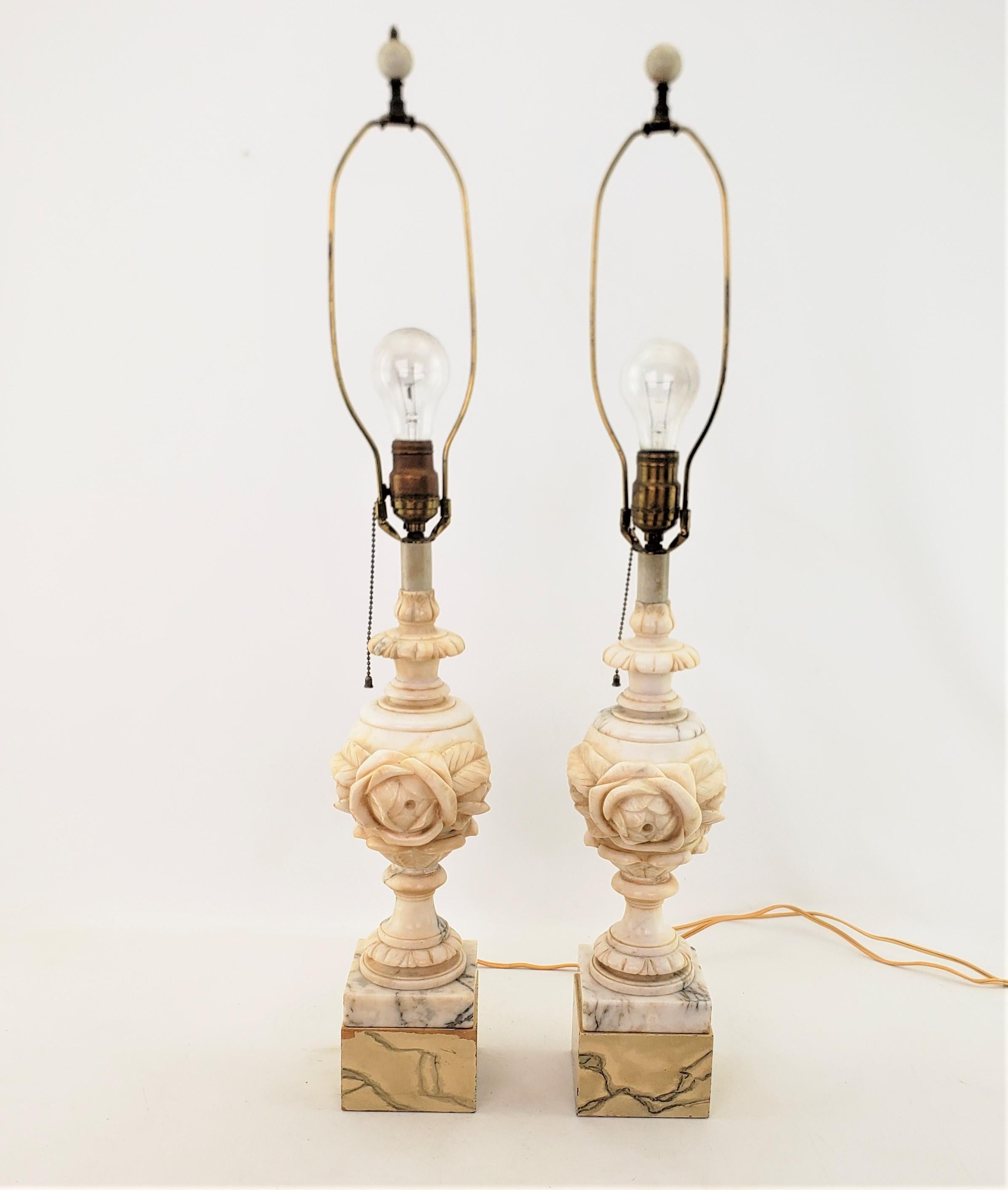 This pair of antique lamps are unsigned, but presumed to have originated from Italy and date to approximately 1920 and done in a Neoclassical Revival style. The lamps are composed of veined alabaster with added wooden block bases with a faux marble