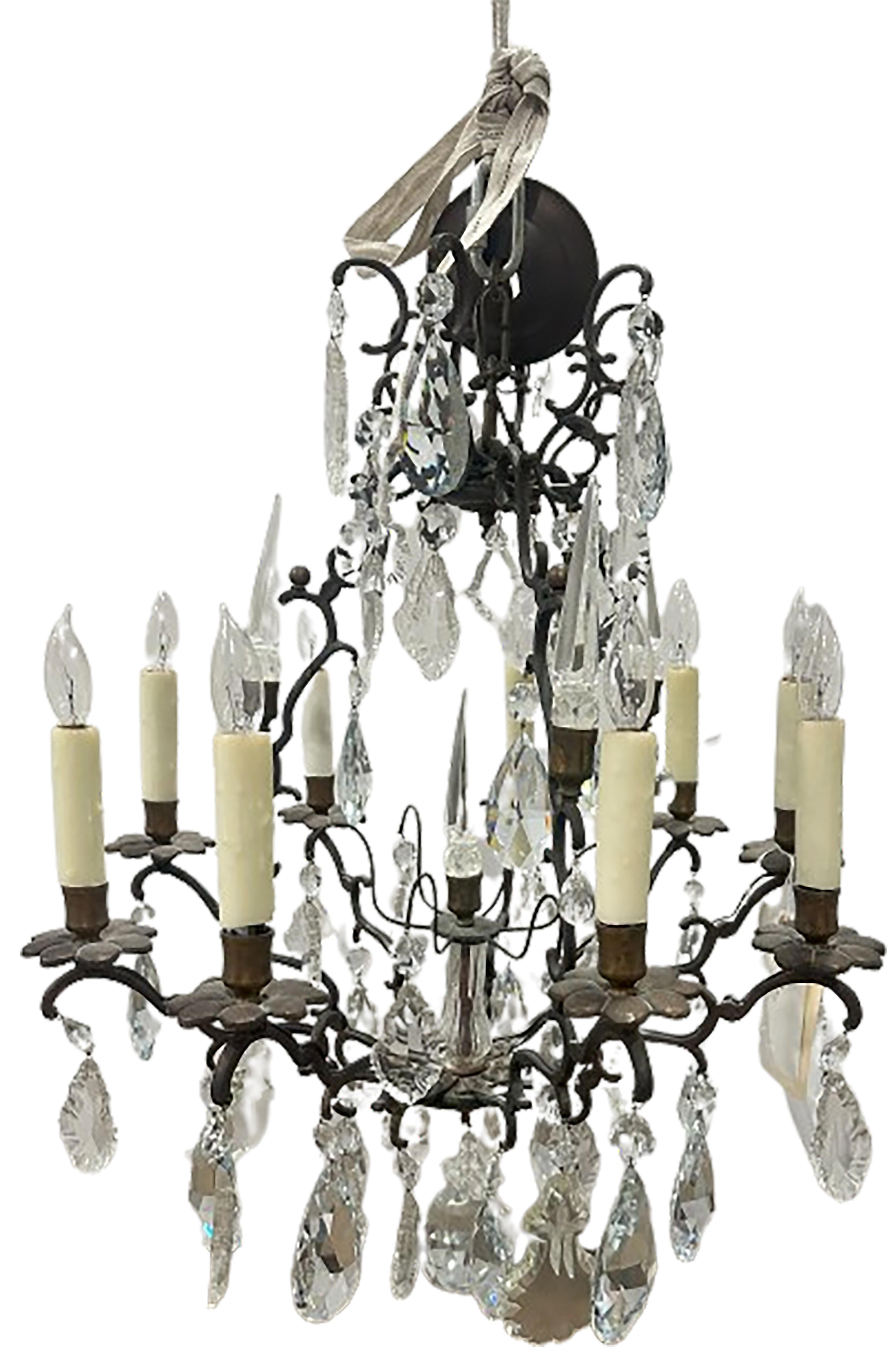 Un'affascinante coppia di antichi lampadari neoclassici Versailles in bronzo dipinto e cristallo Swarovski. Candele elettriche finte cablate. Il cristallo tagliato in modo elegante è drappeggiato dalla struttura in bronzo. Creato in Francia nel 1940