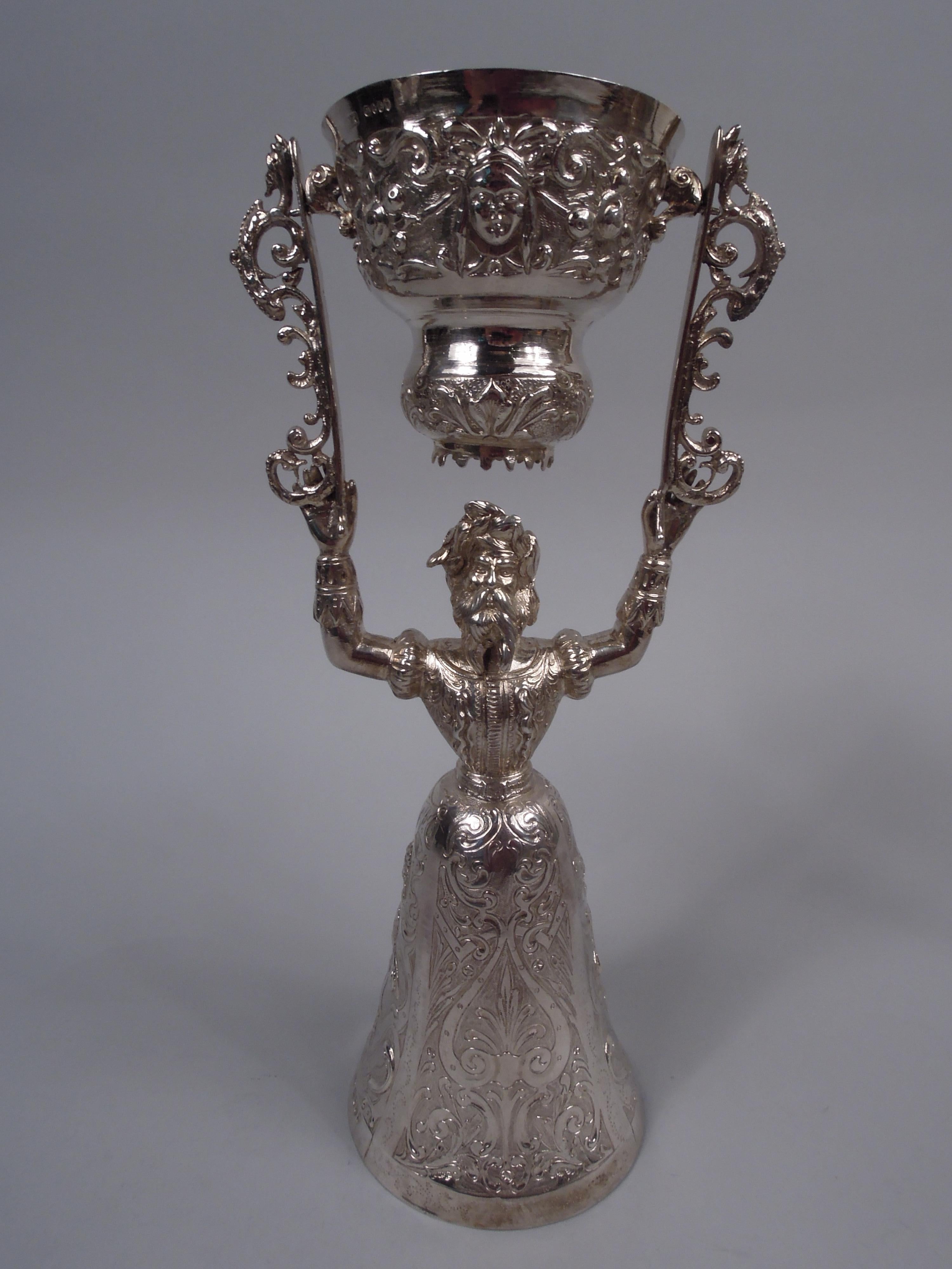 Pair of German silver wedding cups. Imported to England by Martin Sugar in 1891. Each: Snug-fitting bodice and raised arms holding aloft scrolled brackets with swing-mounted double-domed bowl. Larger bowl in form of skirt. Chased and engraved