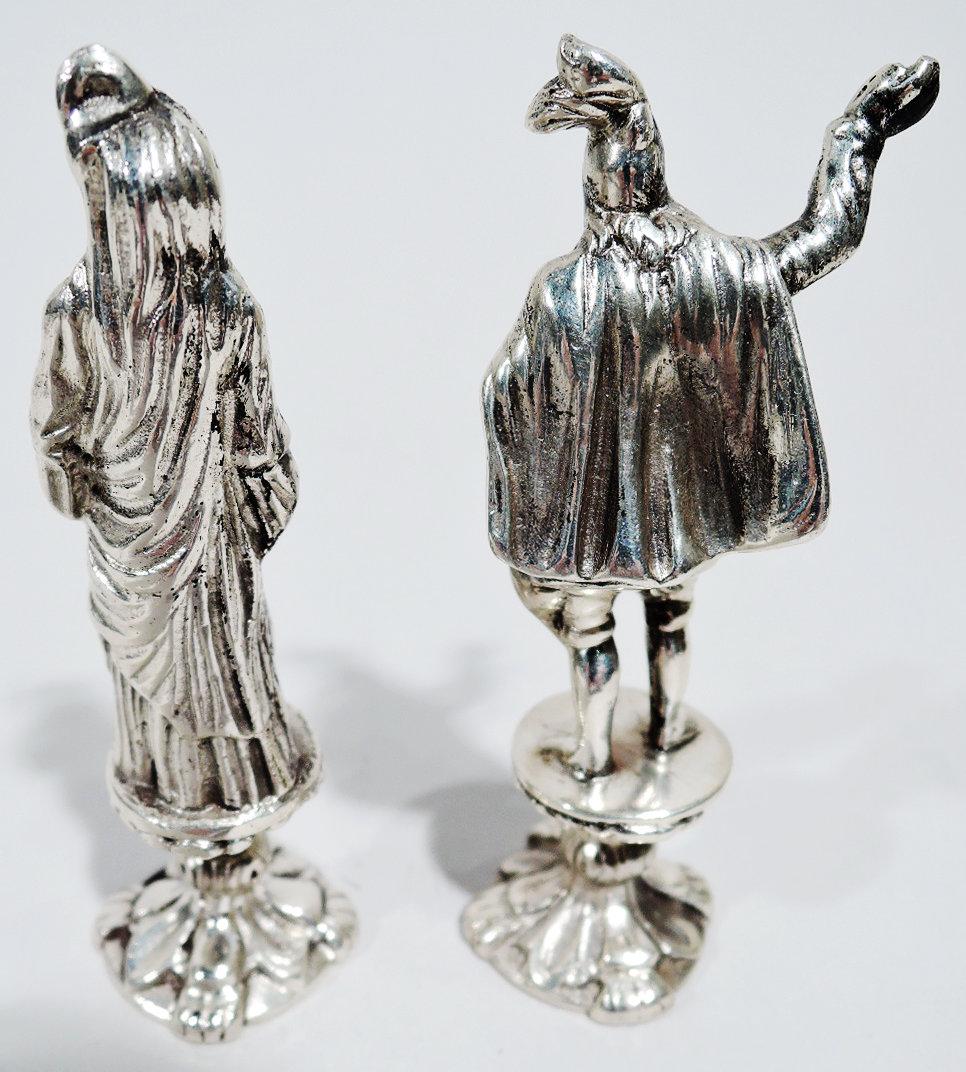 Coppia di statuette storiche in argento tedesco 800, 1910 circa. L'uomo in doppietta, manichetta ed elmo piumato fa un gesto drammatico. La donna in abito sciolto e drappeggiato è in piedi in una posa di pudico autocontrollo. I marchi includono il