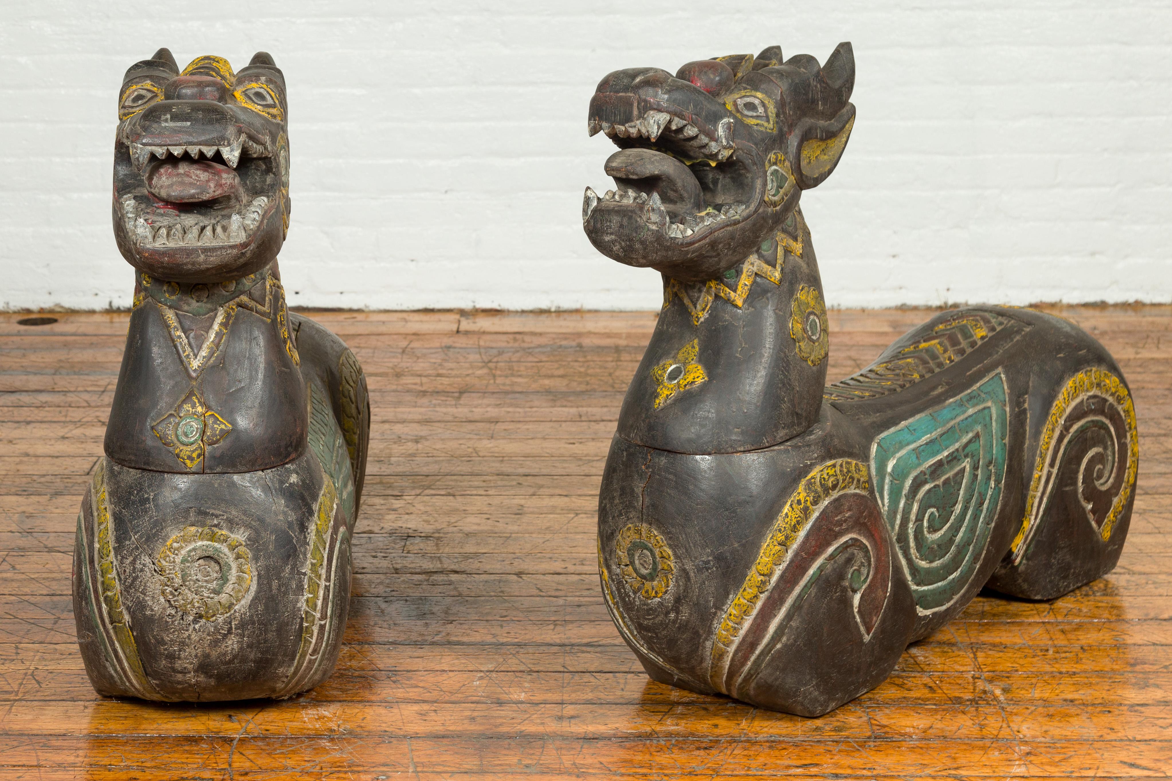 A pair of antique Chiang Mai wood mythical guardian animals from Thailand. Carved in Chiang Mai, Northern Thailand, this pair of mythical guardian animals attracts our attention with their striking features and polychrome finish. Made of old wood,