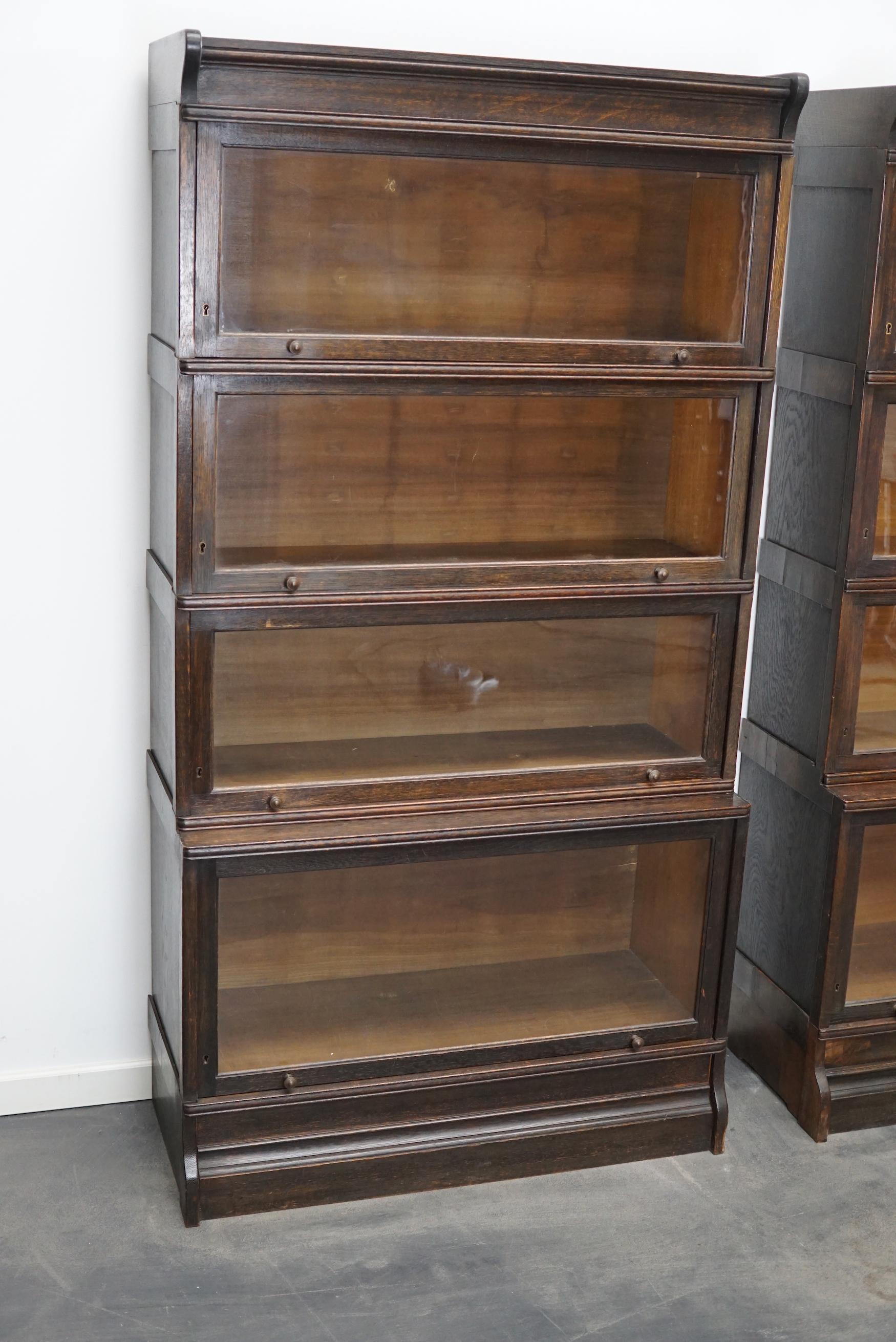 This pair of bookcases were produced by Muller in the Germany around 1930. They feature stackable compartments with glass sliding doors. The interior dimensions of the compartments are: DWH 24 x 80 x 26 cm and 31 x 80 x 34 cm.