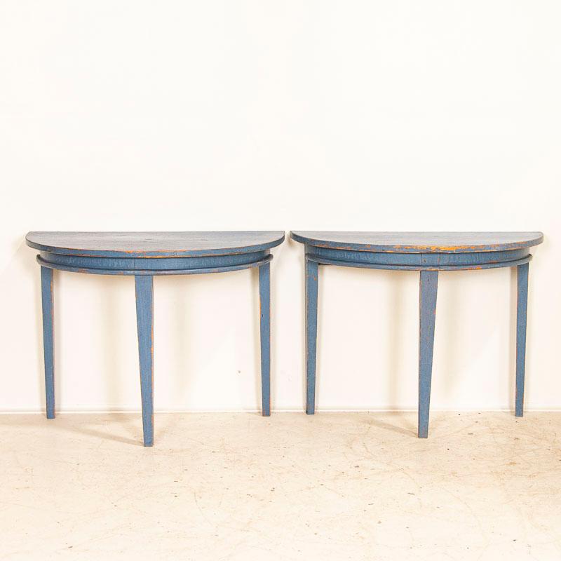 This delightful set of 2 demilune tables is a lovely find. Notice in the close up photos the original blue painted finish with Fine, aged crackling throughout and distressed areas revealing the natural pine below which reflect generations of use.