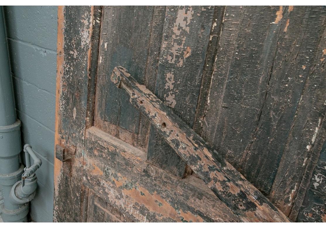 A pair of antique doors with arched and paneled design with remnants of old green and other encrusted paint. The doors do have some old hinges and hardware as shown. Also a horizontal cross bar that pivots that was used to latch the doors (barely