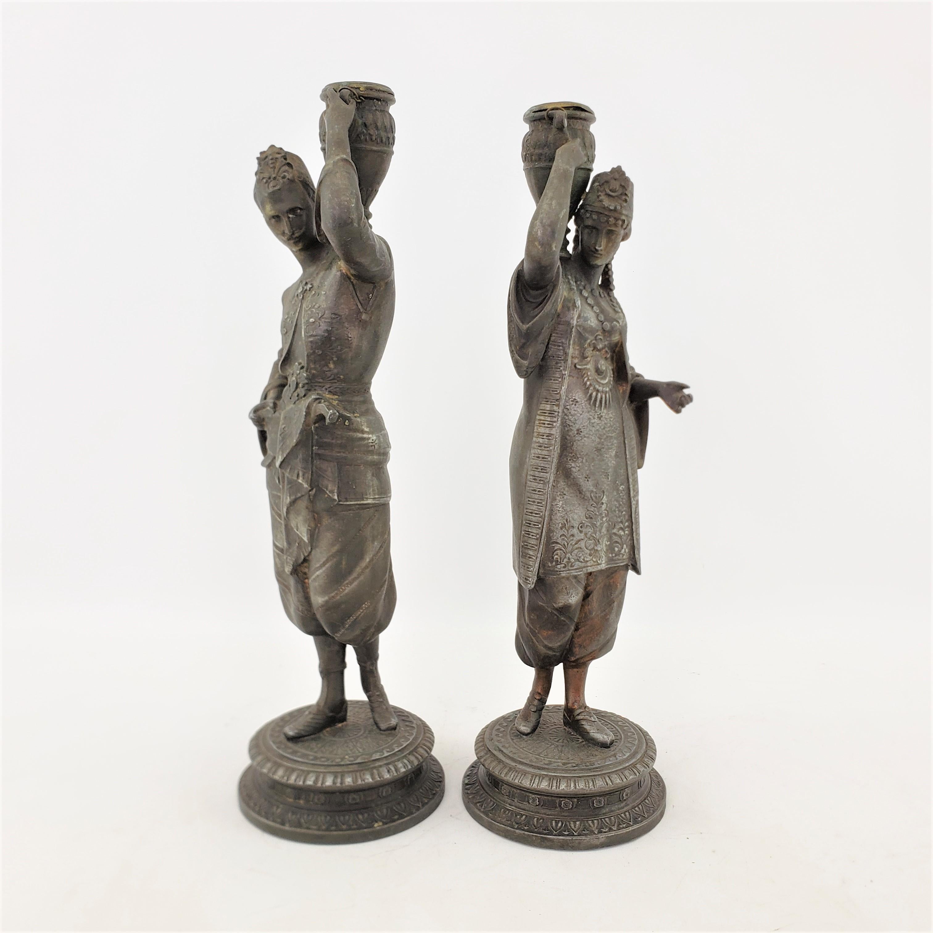 Questa coppia di candelieri antichi non è firmata, ma si presume che provenga dall'Austria e che risalga all'incirca al 1900, in stile Neoclassico Revival. Questi candelieri scultorei sono composti da spelta con una finitura patinata e sono molto