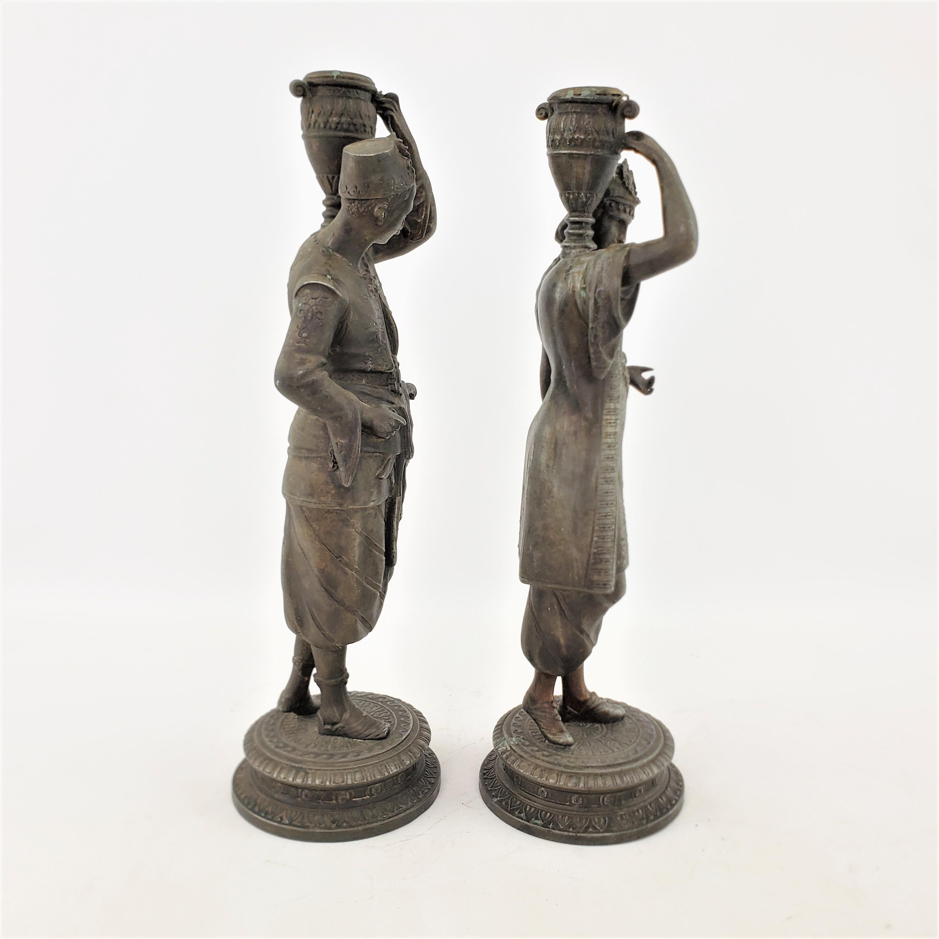 Cast Pair of Antique Patinated Spelter Candlesticks of a Man & Woman Carrying Water For Sale