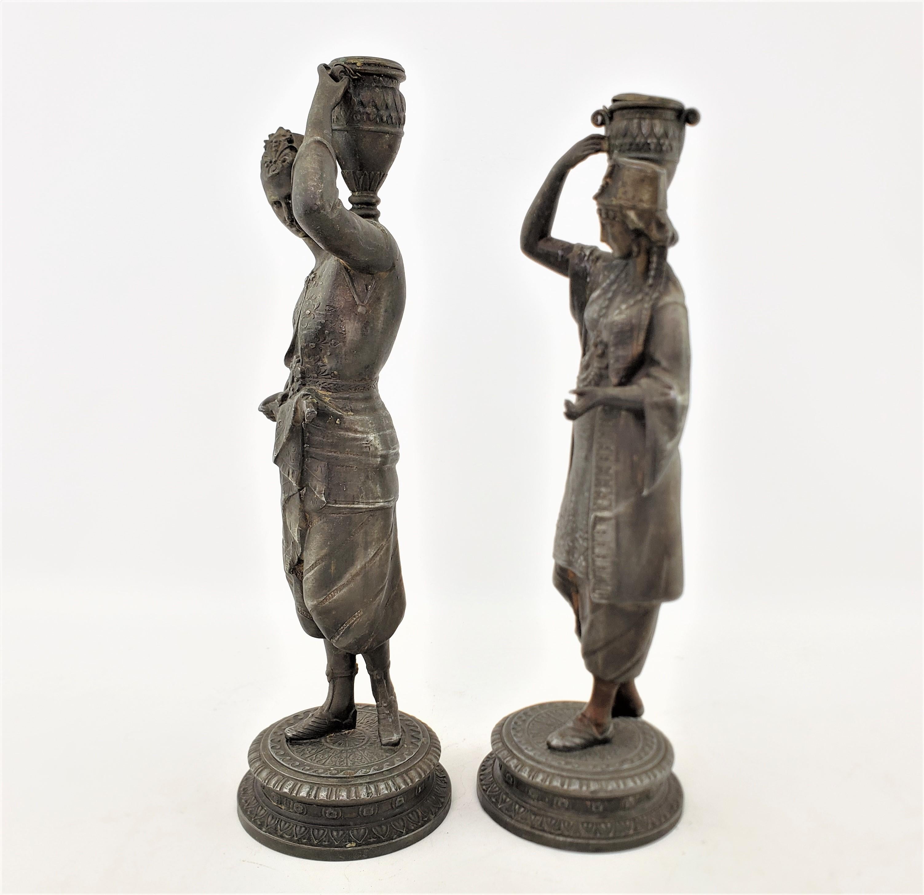 Paar antike Kerzenständer aus patiniertem Zinn mit einem Mann und einer Frau, die Wasser transportieren (Gegossen) im Angebot