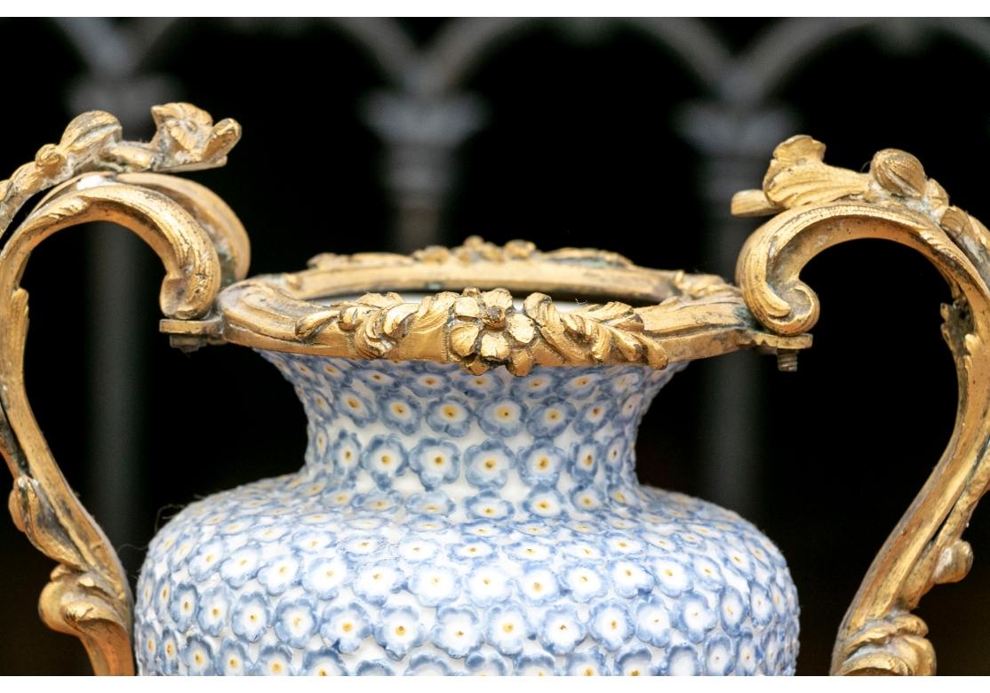 Paire de vases anciens en céramique montés sur bronze doré ormulu. Les vases sont de forme balustre et présentent de magnifiques décorations florales moulées et peintes en relief. 

Condit : Les vases en porcelaine présentent des éclats et des nics