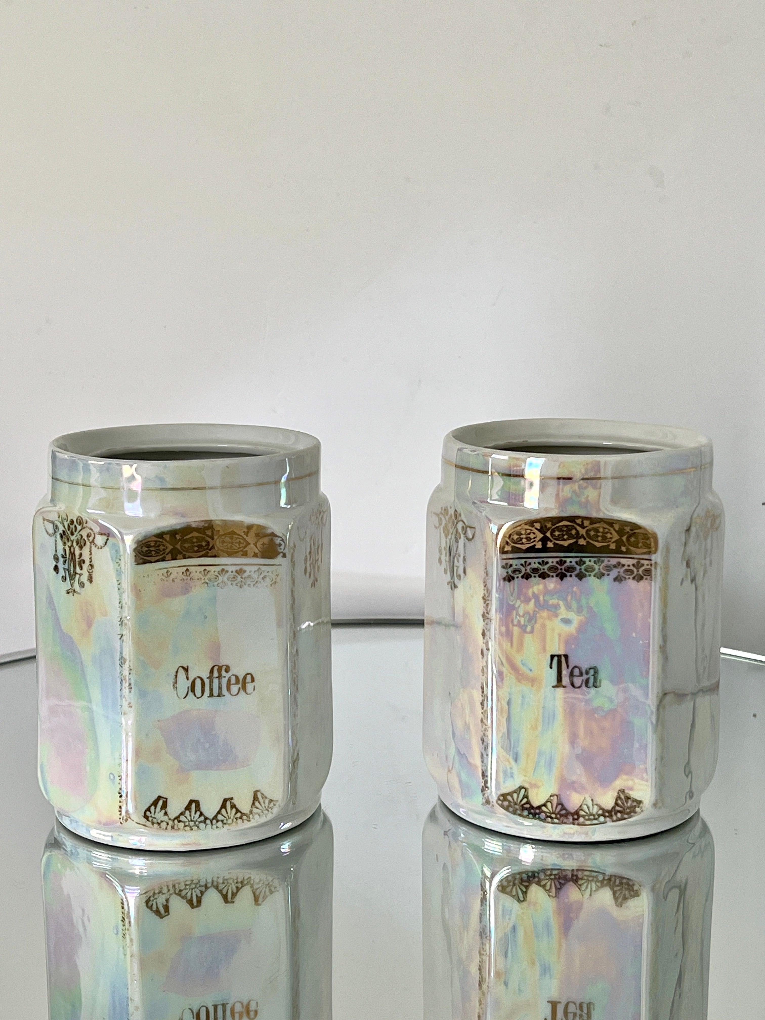 Handmade antique porcelain apothecary and spice canisters. Hand-painted in 24K gold leaf with iridescent metallic glaze or lusterware.  The coffee and tea jars have stylized floral motifs with geometric patterns. Stamped and signed Germany on