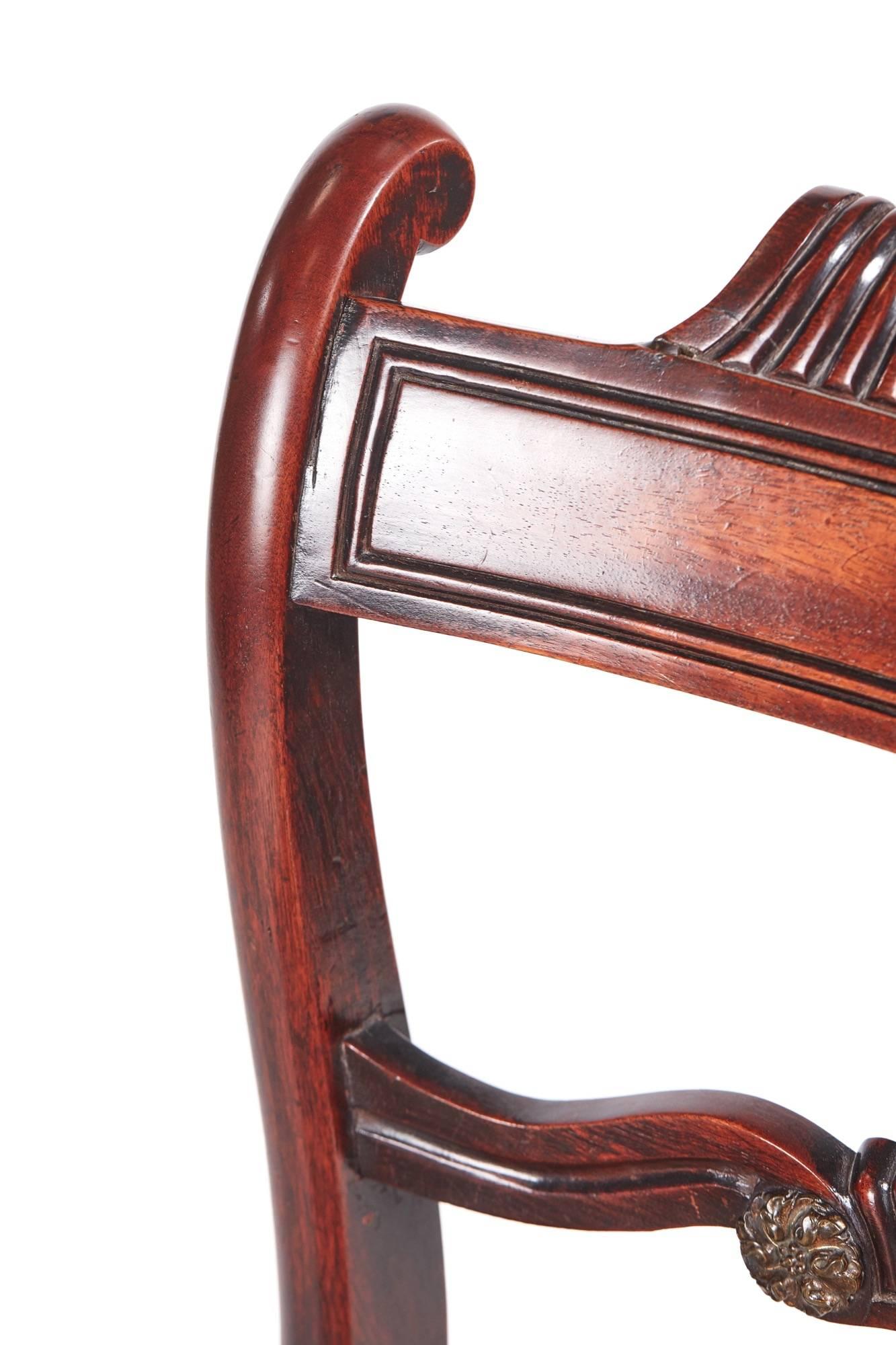 Pair of antique Regency mahogany side chairs, with a shaped carved and reeded top rail, carved centre rail, standing on elegant sabre legs.