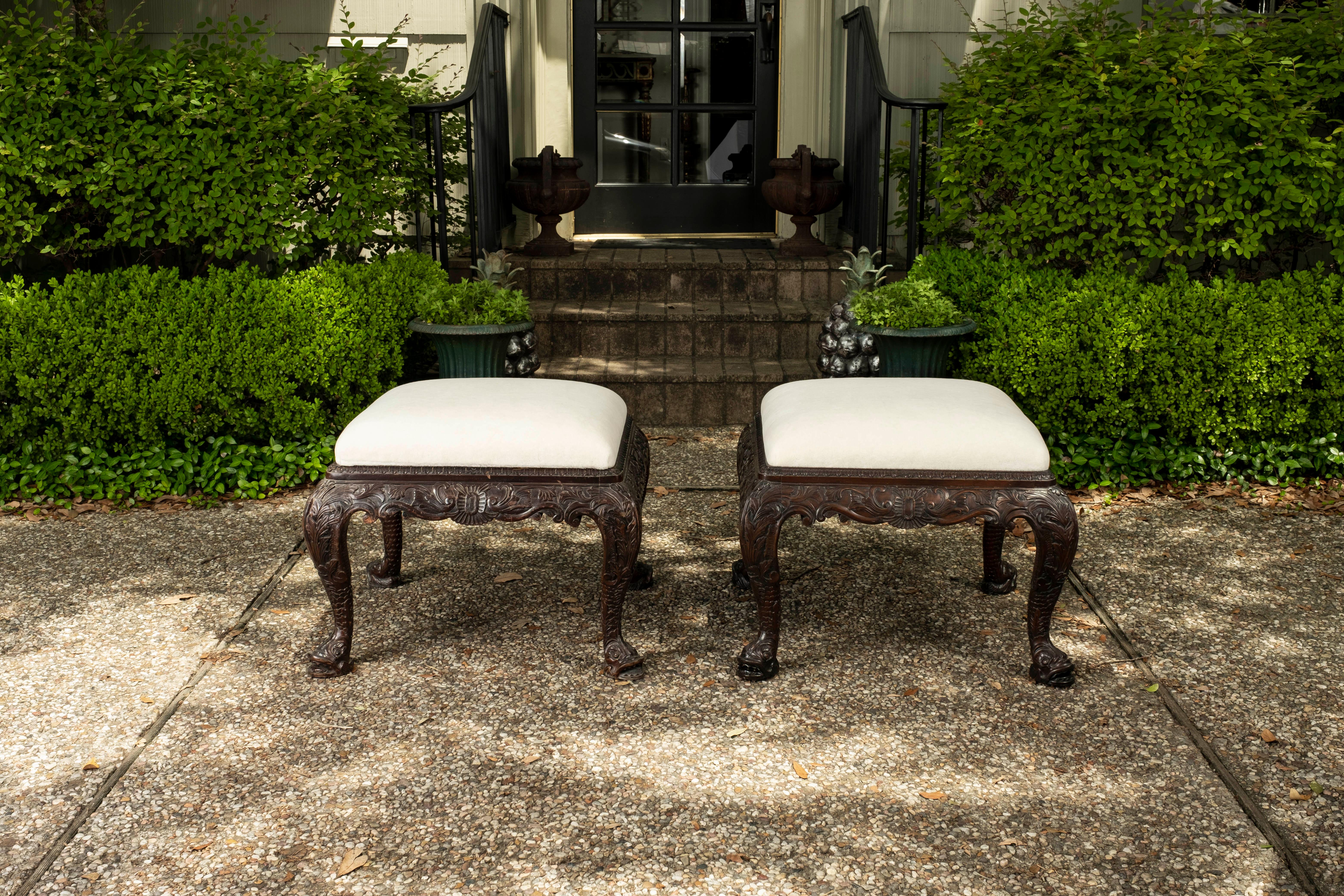 Pair of antique Regency style ottomans or benches. These stunning large English Regency style benches or ottomans are beautifully carved on all sides with lovely dolphin feet. This pair is large enough for extra seating where needed. This pair has