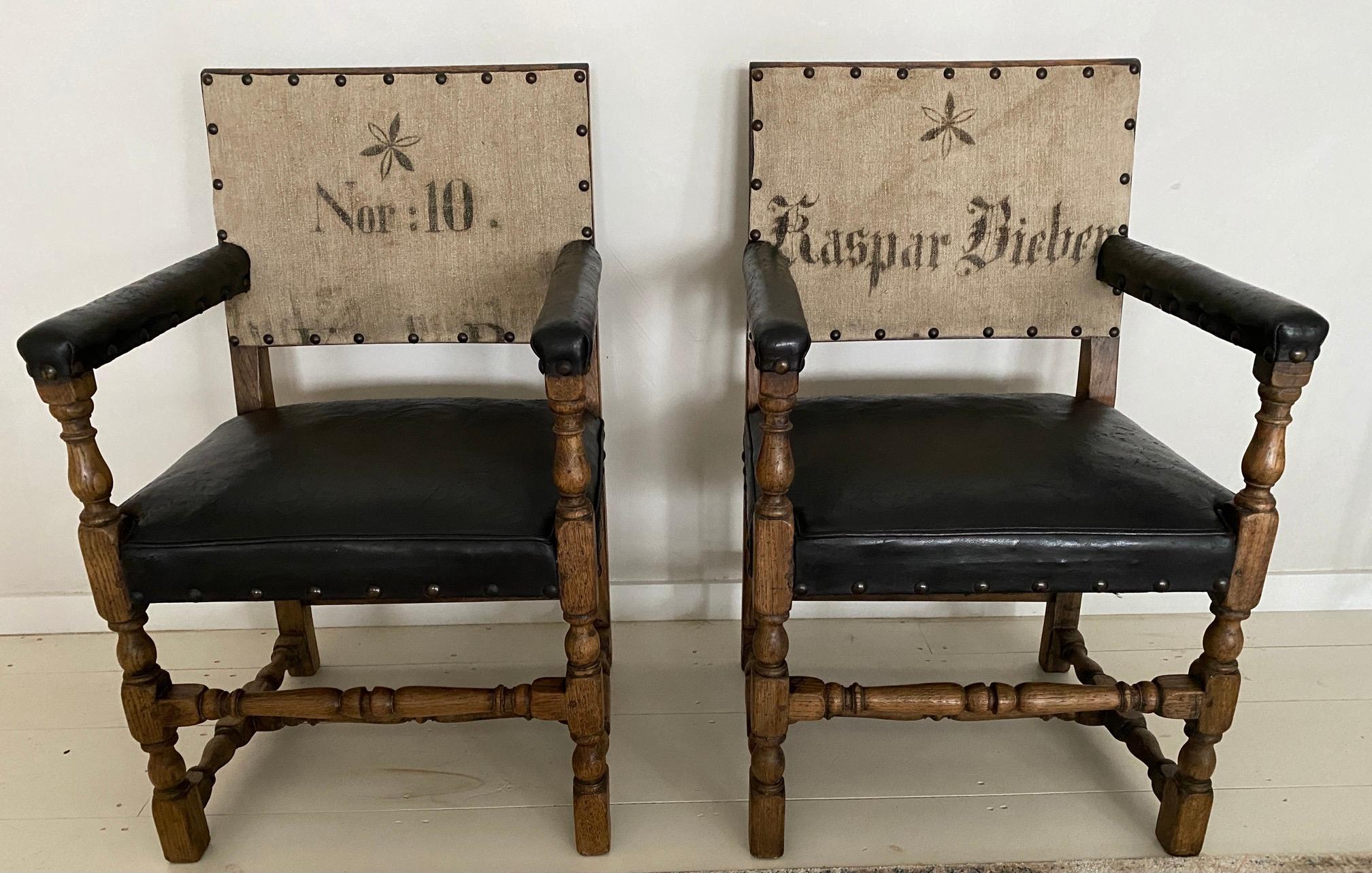 Pair of stately well proportioned square-backed upholstered renaissance style throne chairs with leather upholstered arm rests and seats accented with nail heads on turned uprights legs joined by a conforming front stretchers, constructed of stained