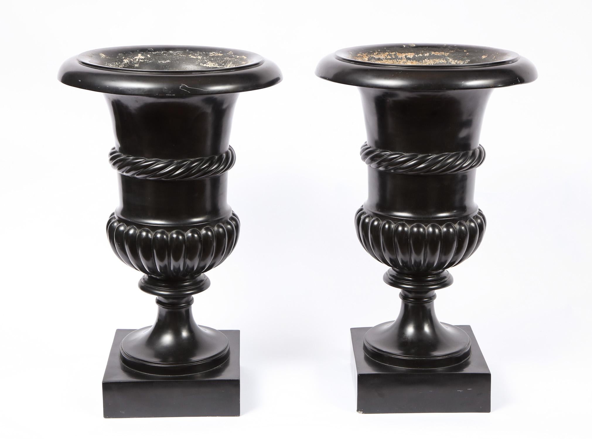 A fine pair of large antique 19th century Roman neoclassical Campagna shaped black Scagliola vases or urns. Seated on a square base, the rim and body of each vase has a meticulously hand-fluted design. Marvelous craftsmanship has gone into each of