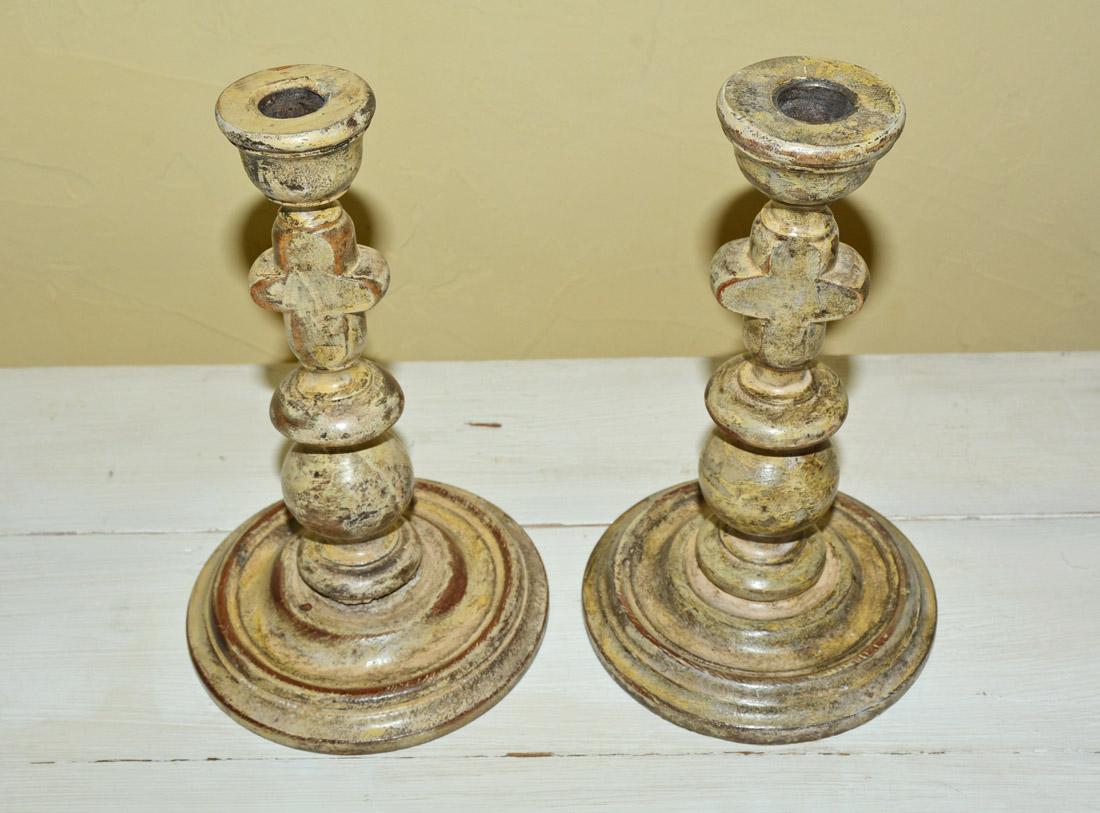 The pair of decorative antique rustic wood candlesticks were hand carved on a lathe and hand painted a rich creamy yellow color. Wonderful for a country indoor/outdoor setting.