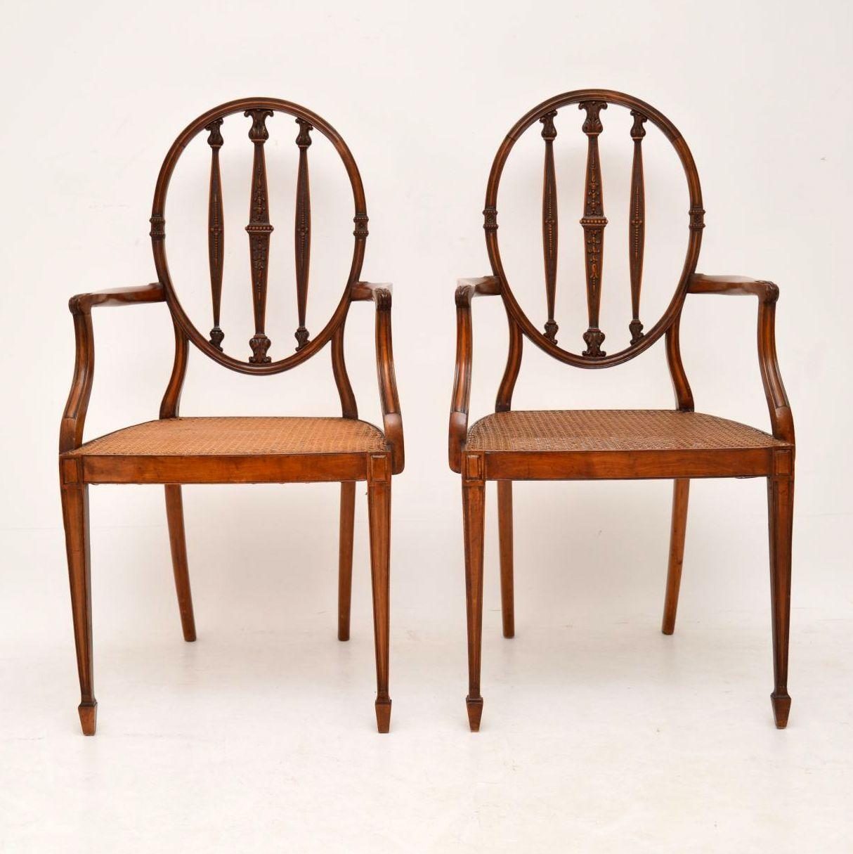 Very elegant and fine quality pair of antique Edwardian Satinwood armchairs of Sheraton design, dating from the 1900-1910 period and in excellent condition. They have oval backs, with intricately carved upright bars & cane seats that are also in