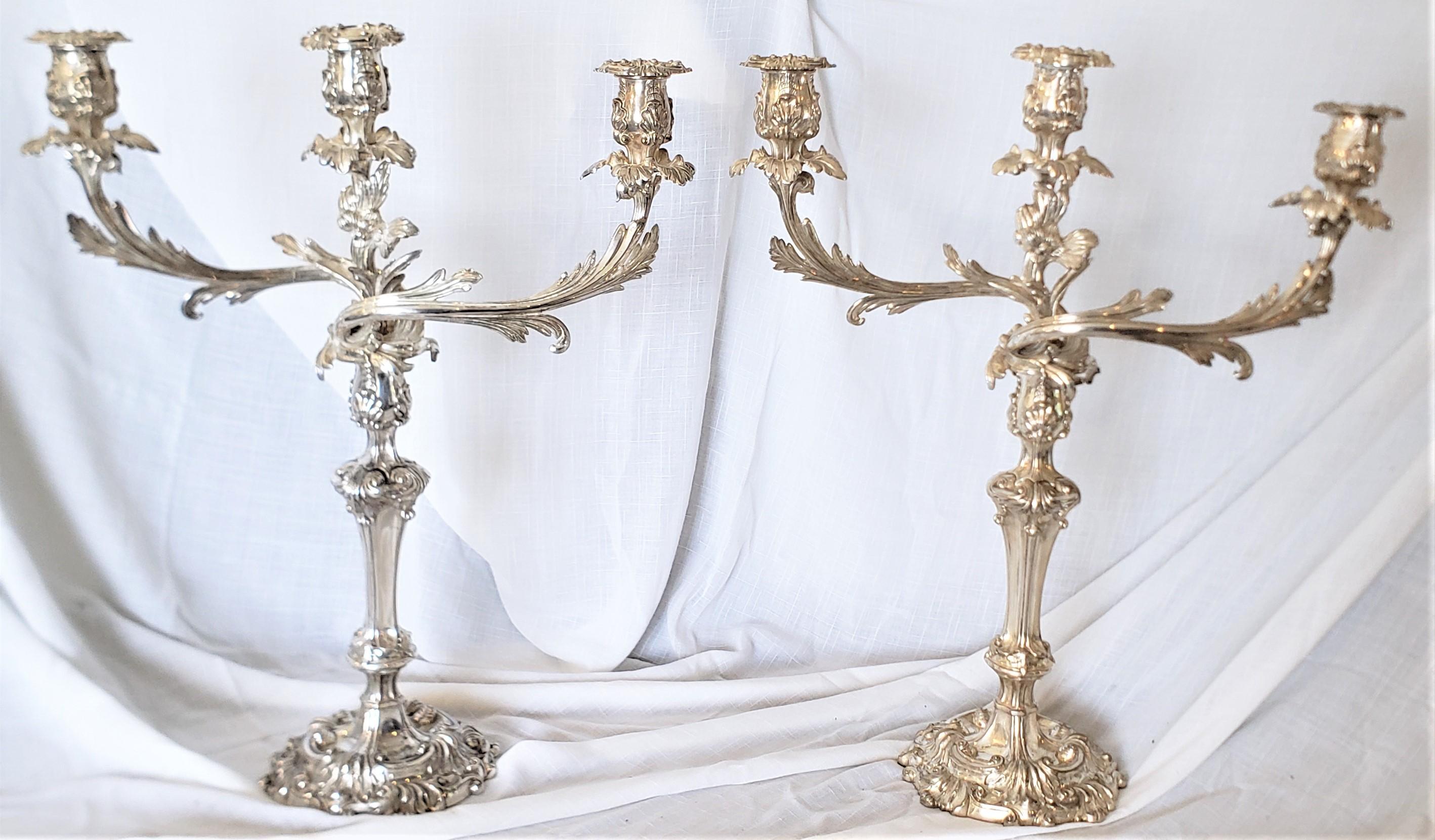 This pair of antique Sheffield plated and elaborately decorated candlesticks are unsigned, but believed to have originated from England from approximately 1830 in a period Victorian style. The candlesticks can be converted from single candle