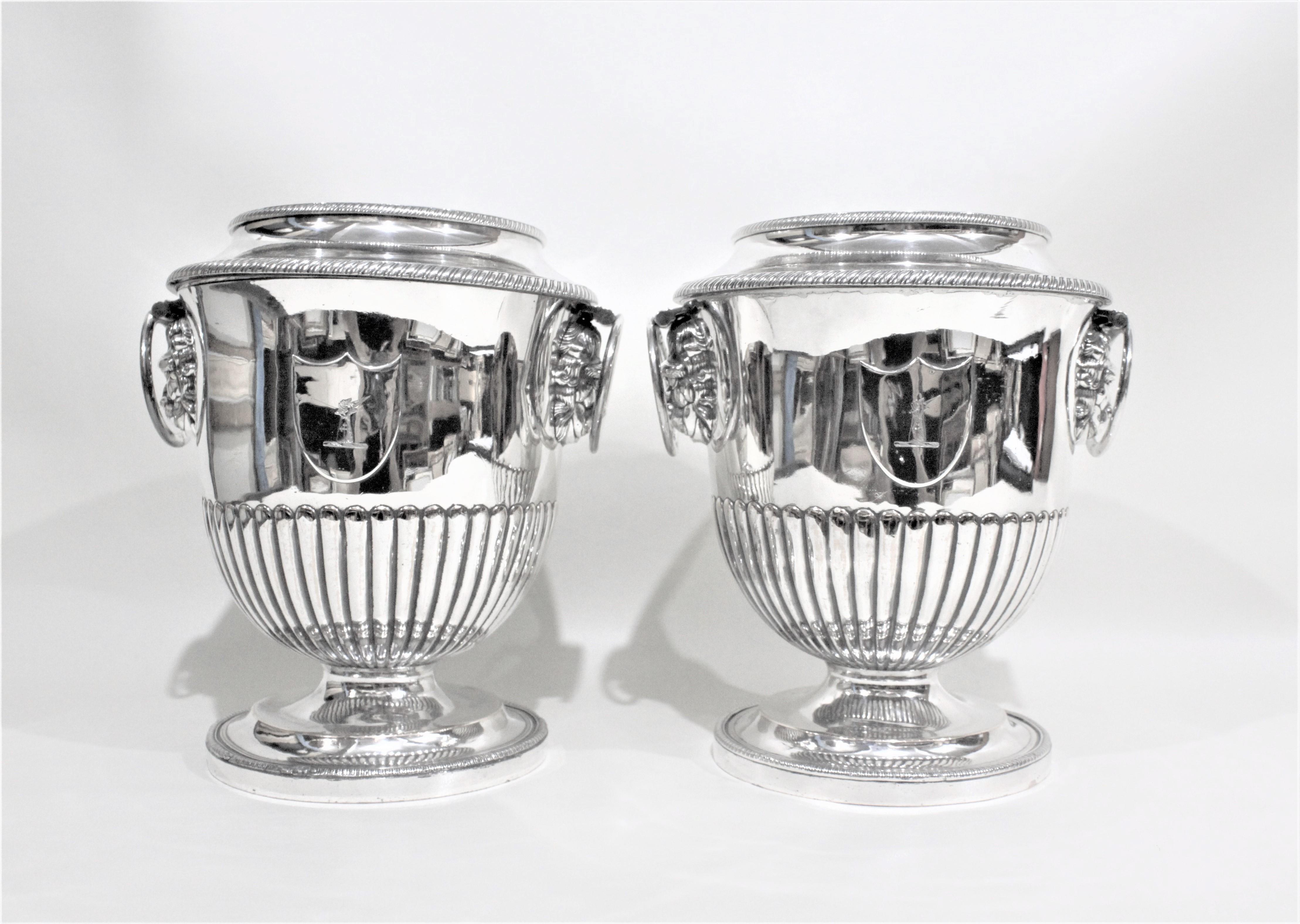 This matched pair of antique wine coolers are unsigned, but presumed to have been made in England between 1800-1820. These wine coolers are done in the Regency style with Sheffield silver plate and have lion head accents under each handle. These