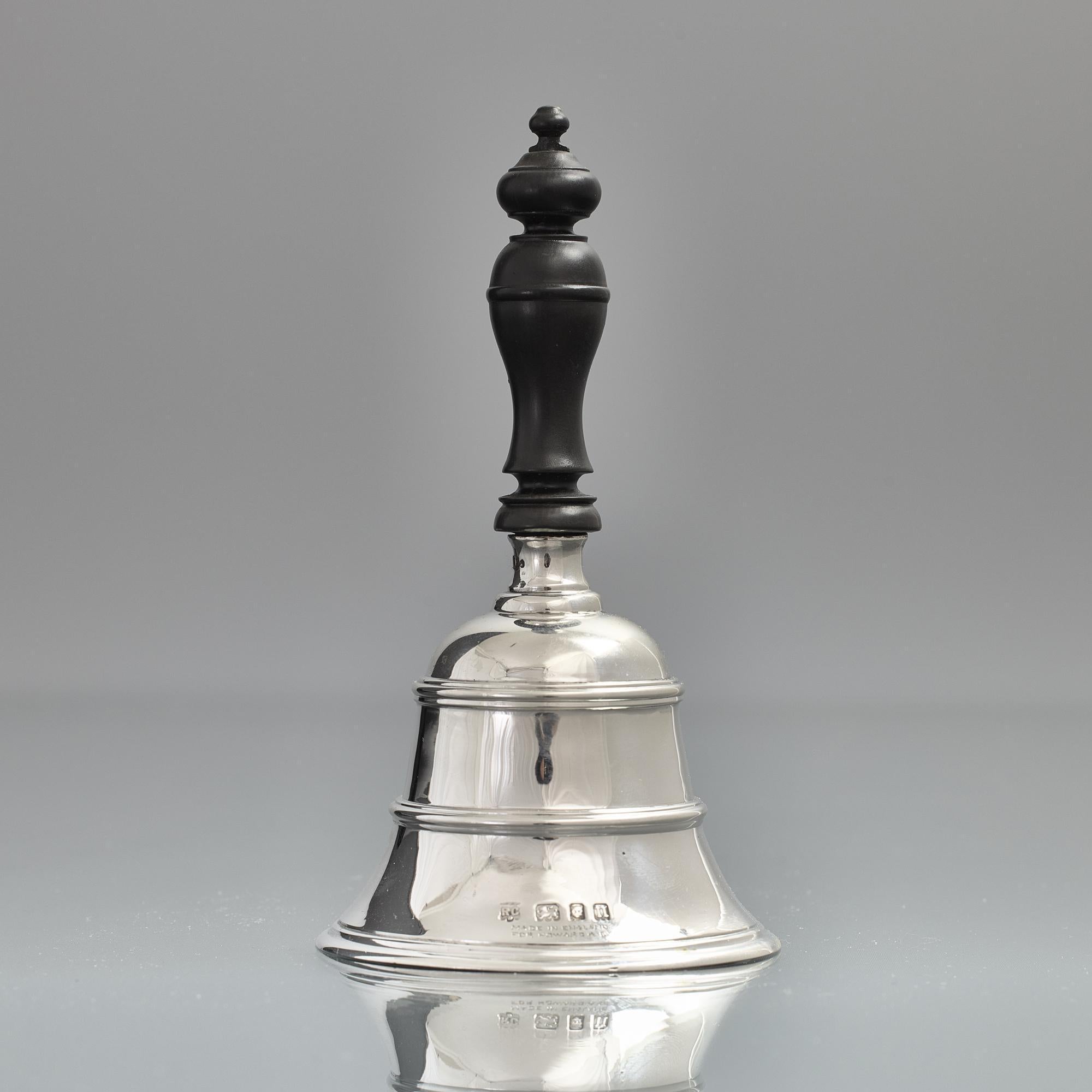 Cloche de table en argent du début du 20e siècle, munie d'une belle poignée en bois dur et d'un crochet qui produit un son délicieux. Le corps évasé en argent sterling moulé est entouré de gaines moulées et appliquées. Il a été vendu à l'origine par