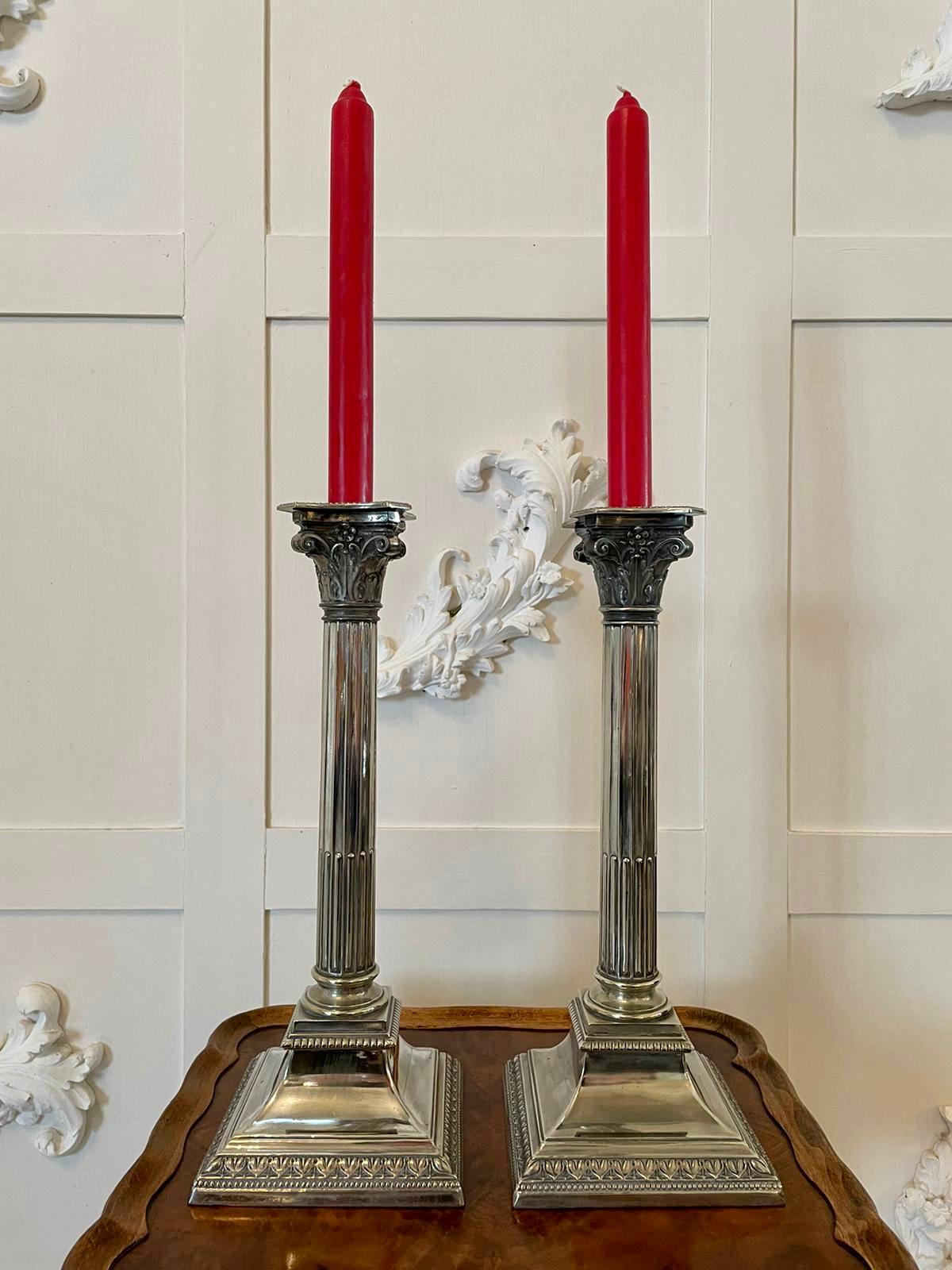 Pair of antique silver plated Corinthian candlesticks having pretty shaped removable sconces to the top and supported by attractive circular reeded Corinthian columns with ornate tops standing on a square shaped ornate stepped base.

Charming