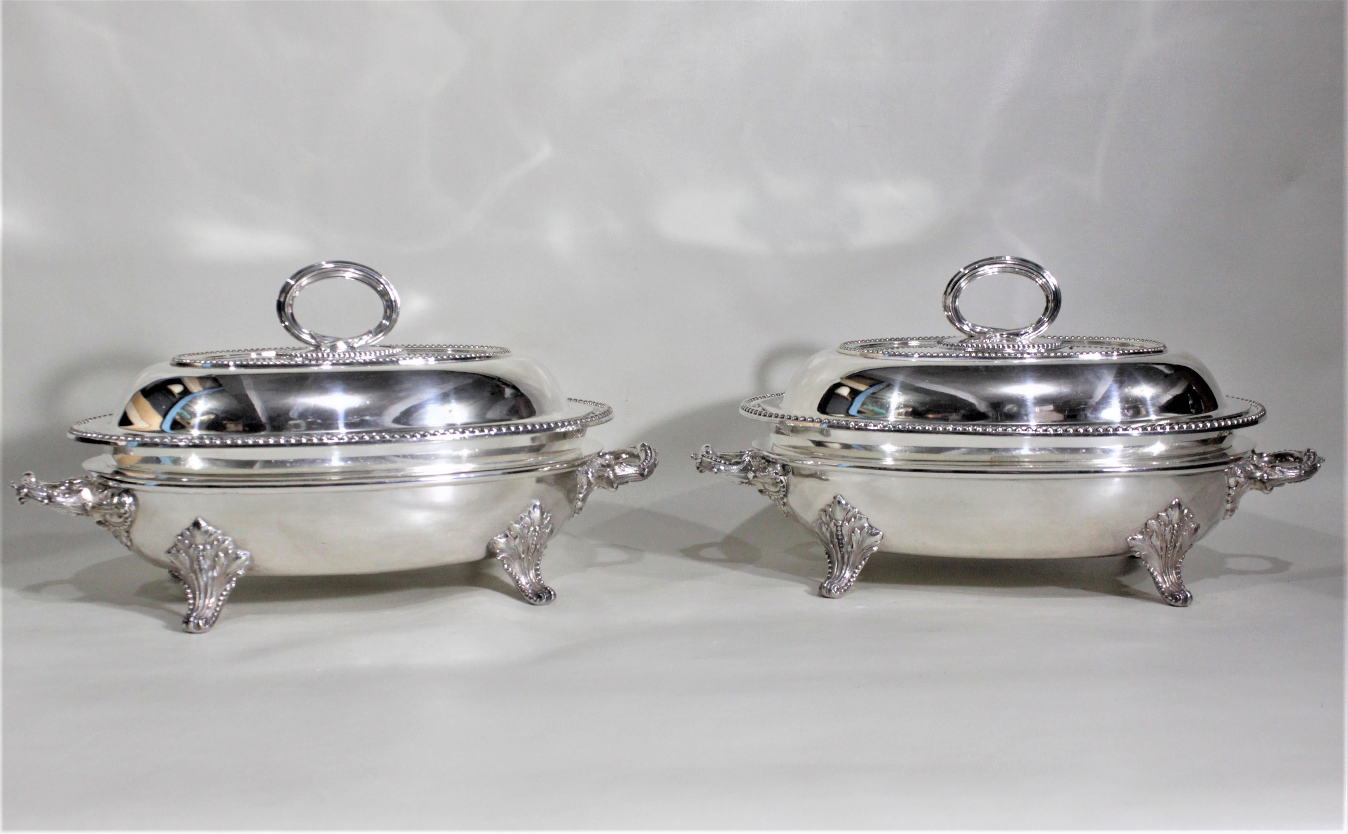 This pair of antique silver plated covered entree servers was made in Sheffield England by the James Dixon and Sons Company in circa 1880 in the period Victorian style. Each server has a heavy footed base with a shallow insert, followed by a serving
