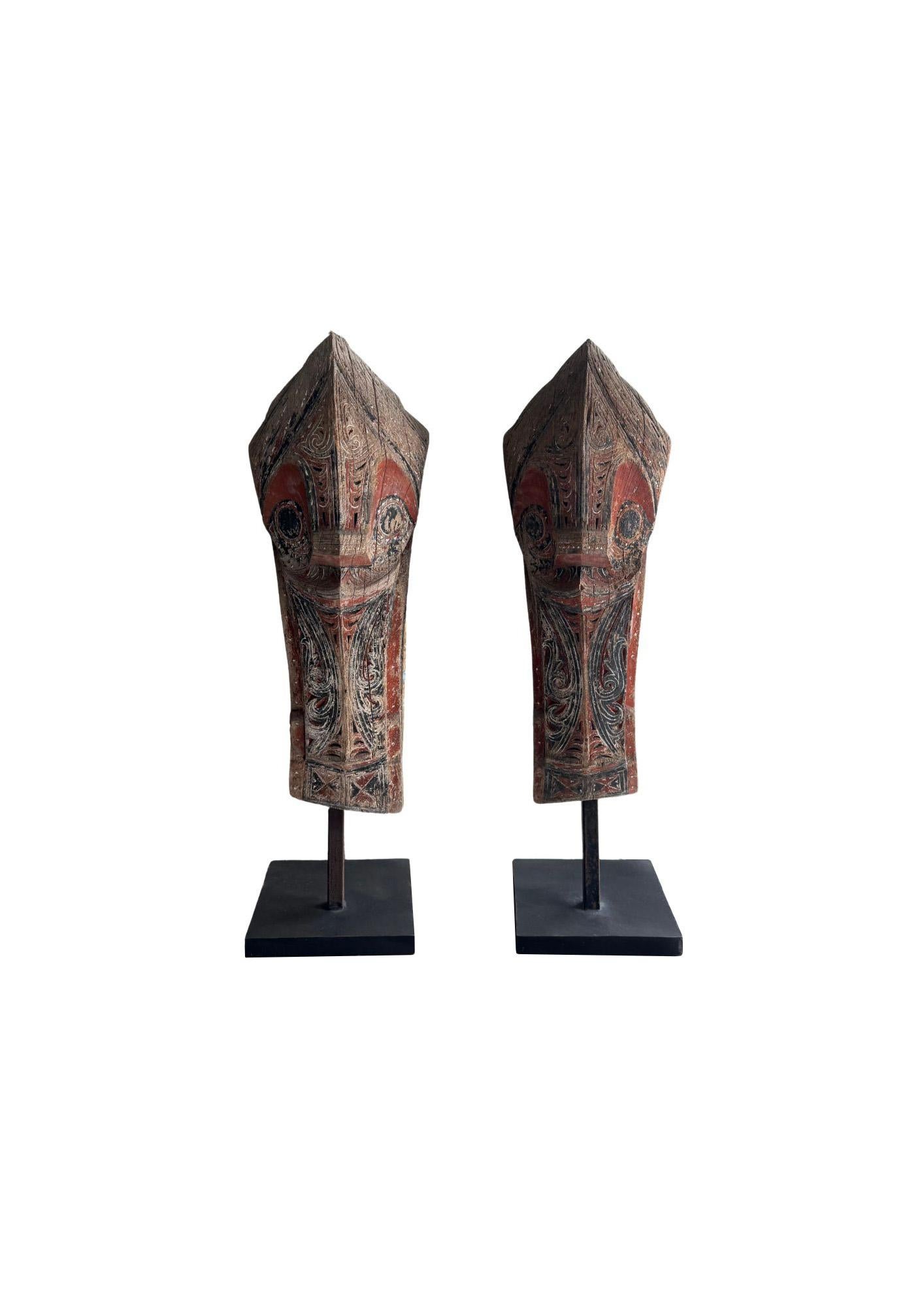 Montée sur un socle en métal peint en noir, cette paire de sculptures anciennes Singa provient de la tribu Batak de Sumatra. Chaque pièce est sculptée dans un seul bloc de bois et présente le motif protecteur emblématique Singa, une créature