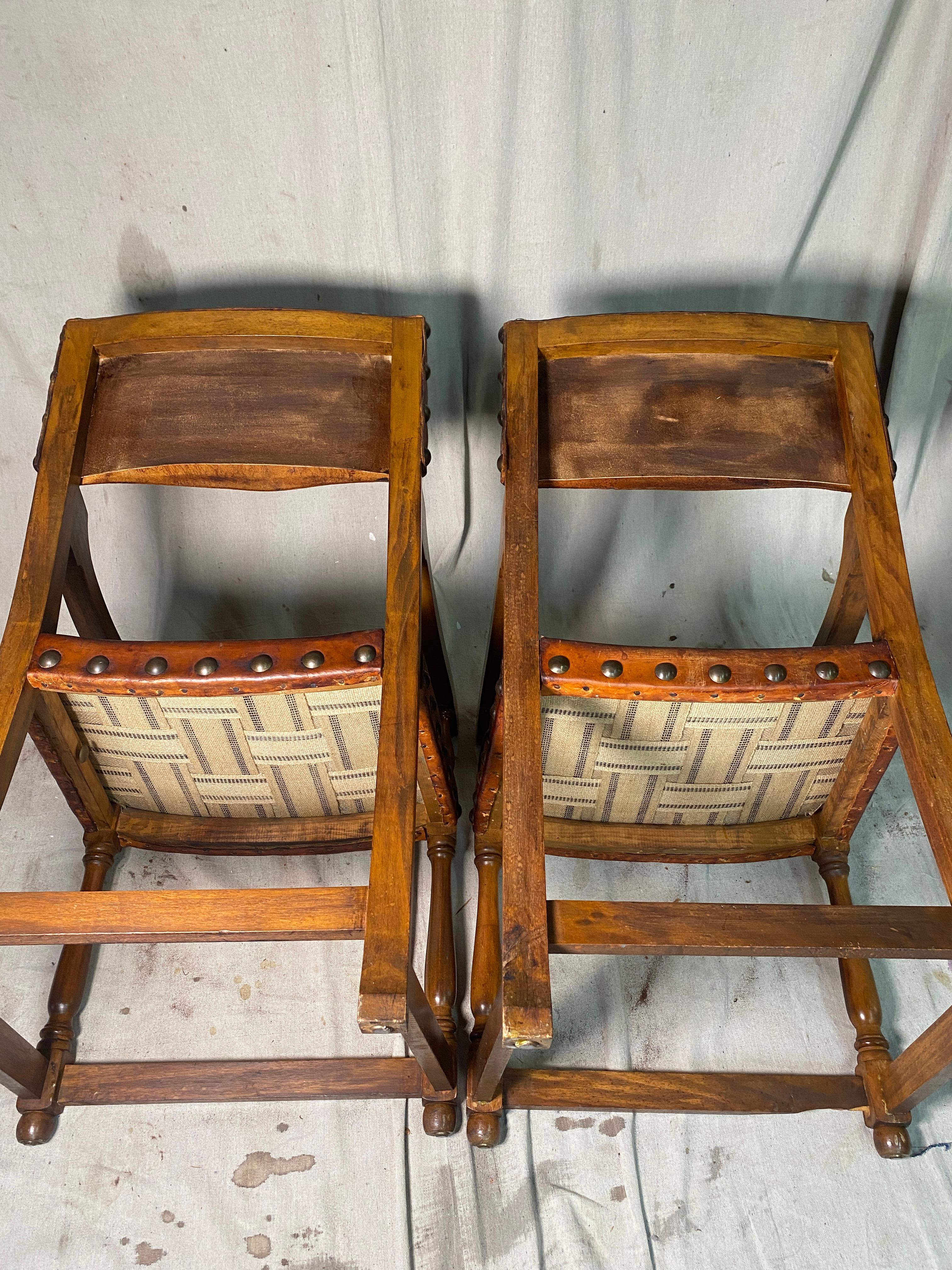 Il s'agit d'une paire de magnifiques fauteuils espagnols anciens en bois et en cuir. Le cuir est d'une riche couleur cognac profond et présente des traces d'usure et de patine - il a été entièrement restauré dans notre atelier. Les têtes de clous en