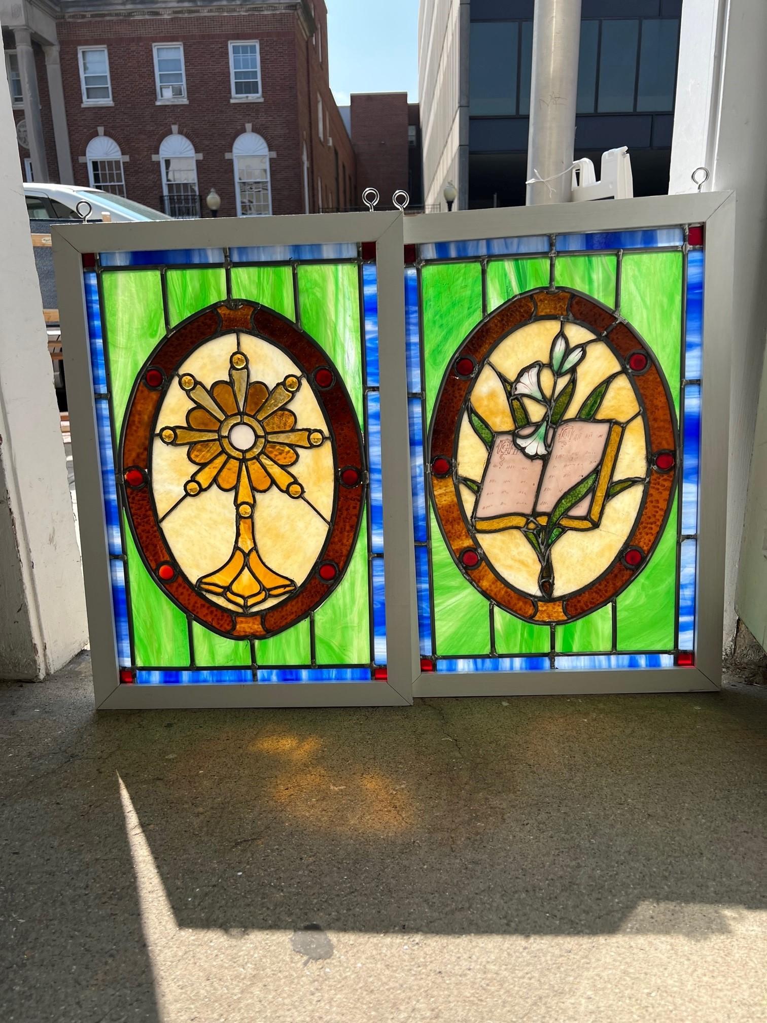 Mid 20th Century pair of stained glass religious windows with new wood frames. This is a nice pair of windows from larger stained glass window that was damaged. One has a monstrance also known as an ostensorium which is the vessel used in the Roman