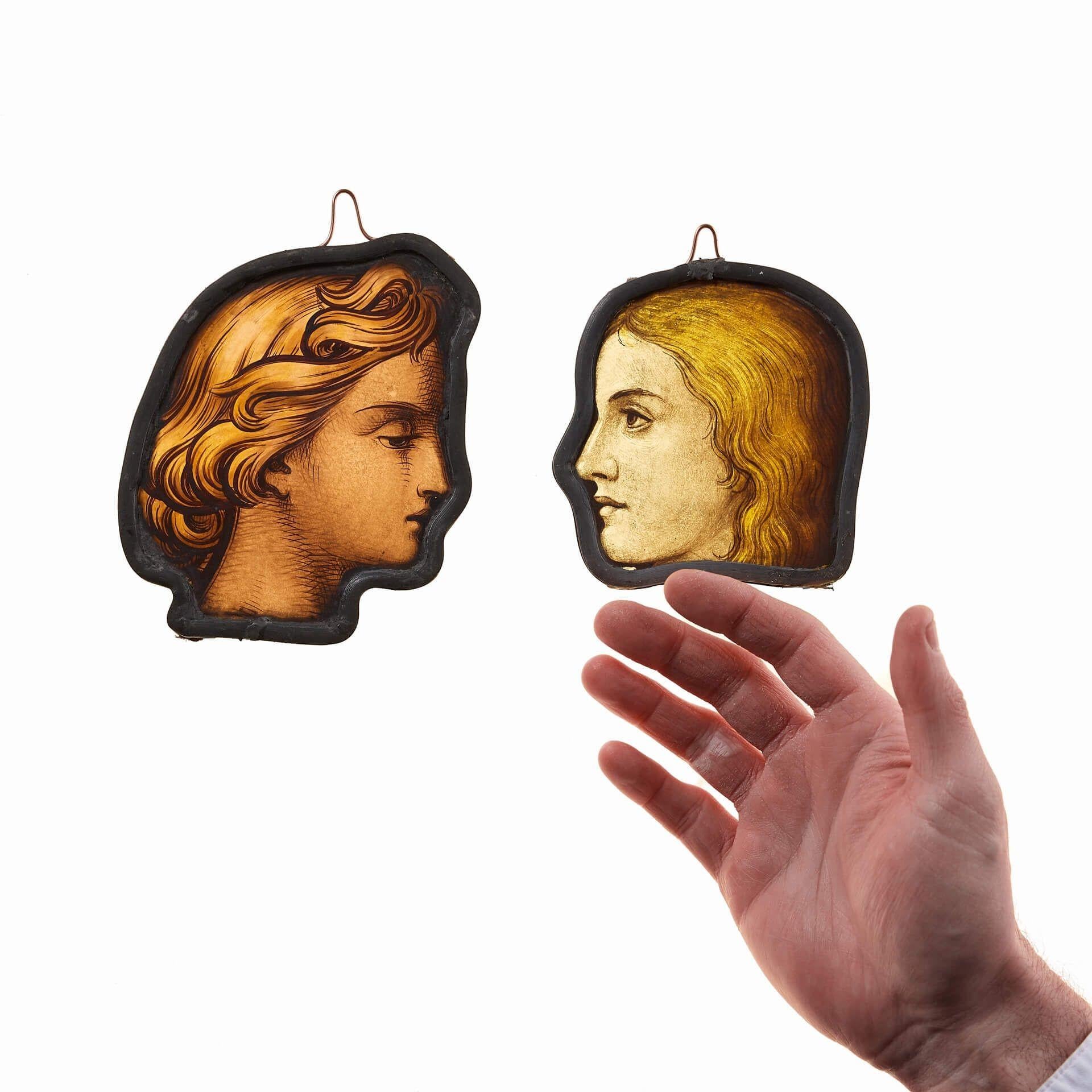 A beautifully painted pair of antique English stained glass window hangings depicting heads in profile, circa 1850. Skilfully handpainted to create a sense of depth and expression, these figures are ideal for hanging in a window or in front of a
