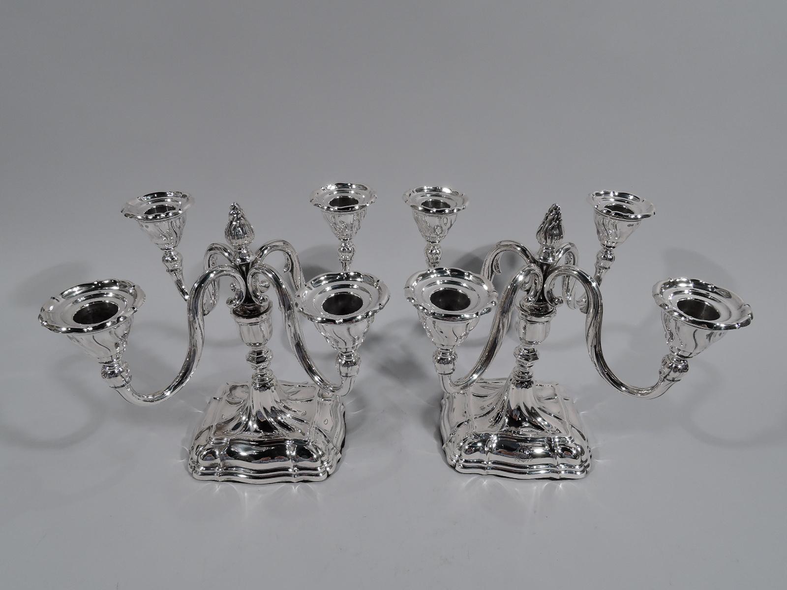 Pair of 4-light sterling silver candelabra, circa 1920. Each: Urn socket on baluster stem mounted to domed and rectangular base. Central bud finial on spool mounted with 4 -scroll arms, each terminating in single socket. Dynamic twisting and