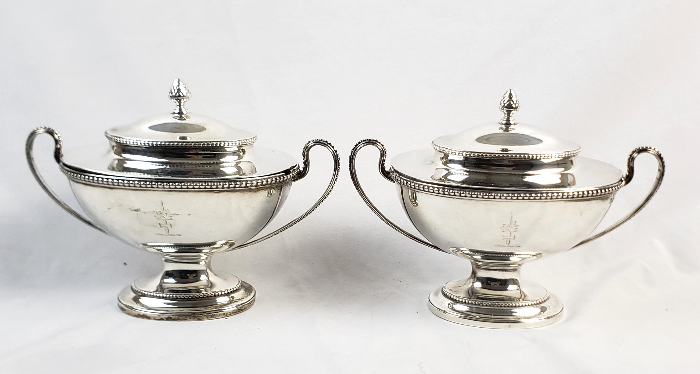 This pair of antique covered sauce tureens are hallmarked by an unknown maker, but originated from England and date to approximately 1820 and done in the period Georgian style. The tureens are composed of sterling silver and have artichoke finials