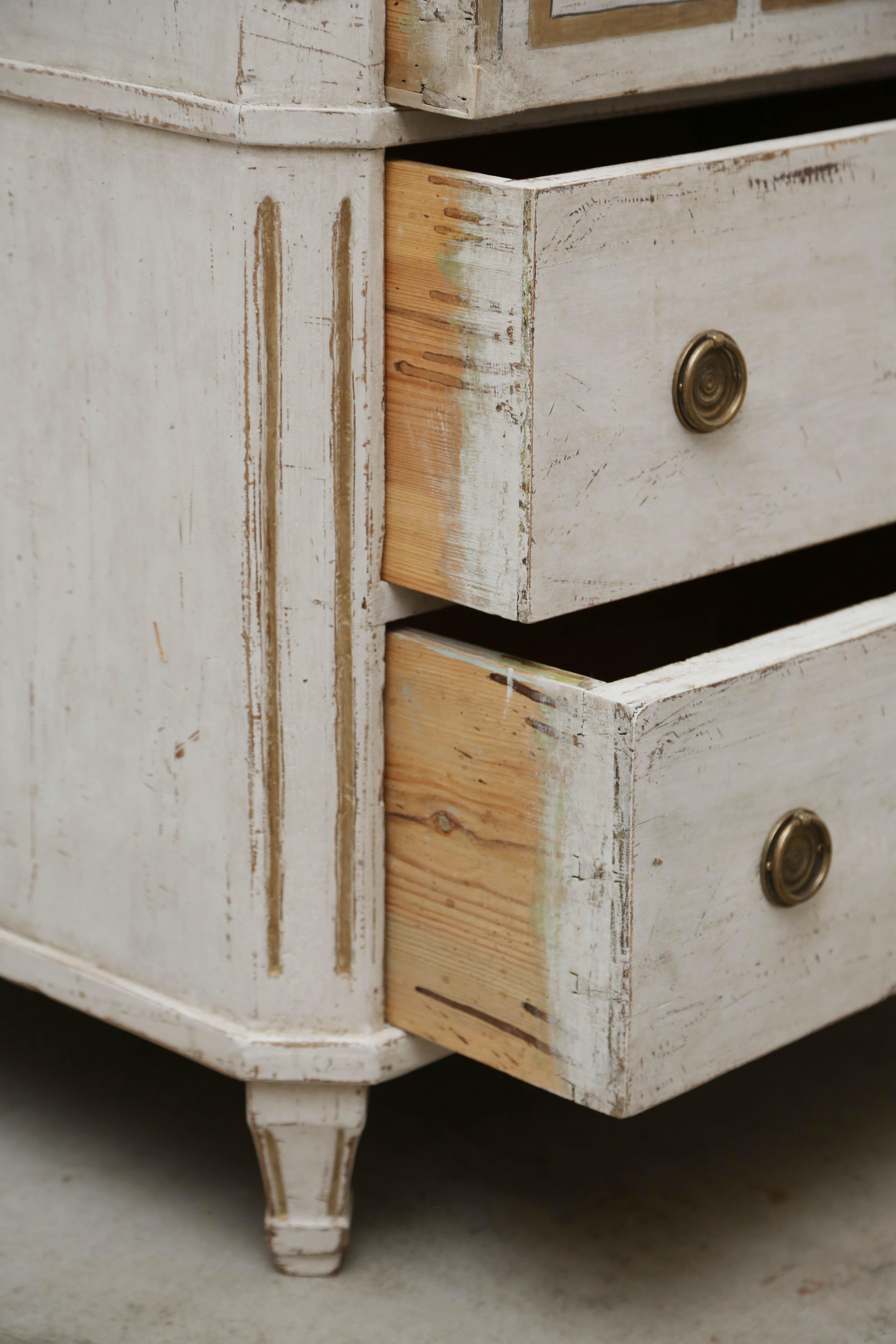 Pair of antique Swedish Gustavian style distressed white painted chests with Greek key gilded border painted on the top drawers of both chests.
Cut off fluted corners and legs with gilded wood carved rosettes at top in the apron.
Chests are painted