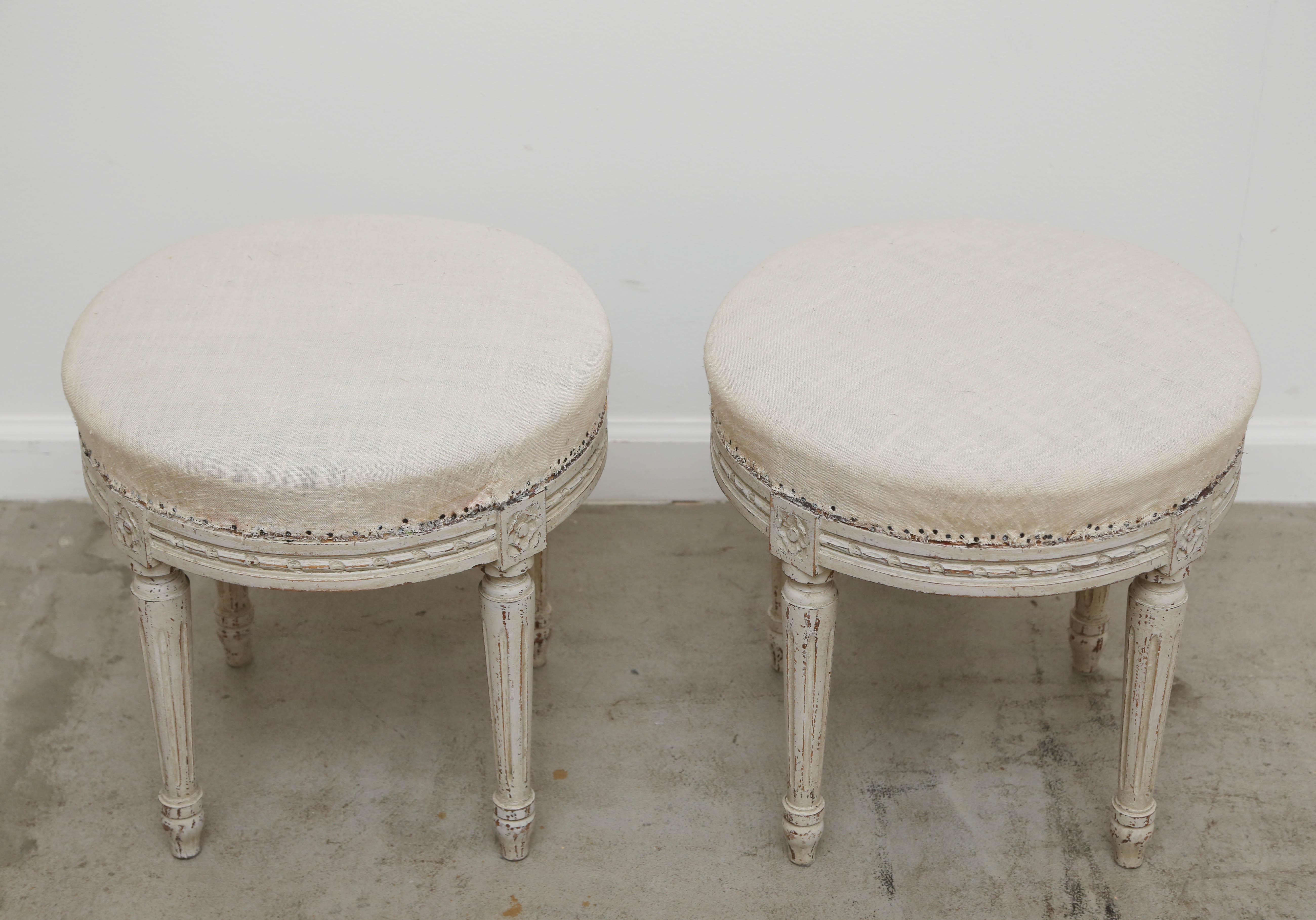 Pair of Swedish Gustavian style white/cream distressed painted stools. With carved rosette on top of each carved round fluted leg. Round seats are filled with original horsehair and covered in period woven muslin fabric,
late 19th