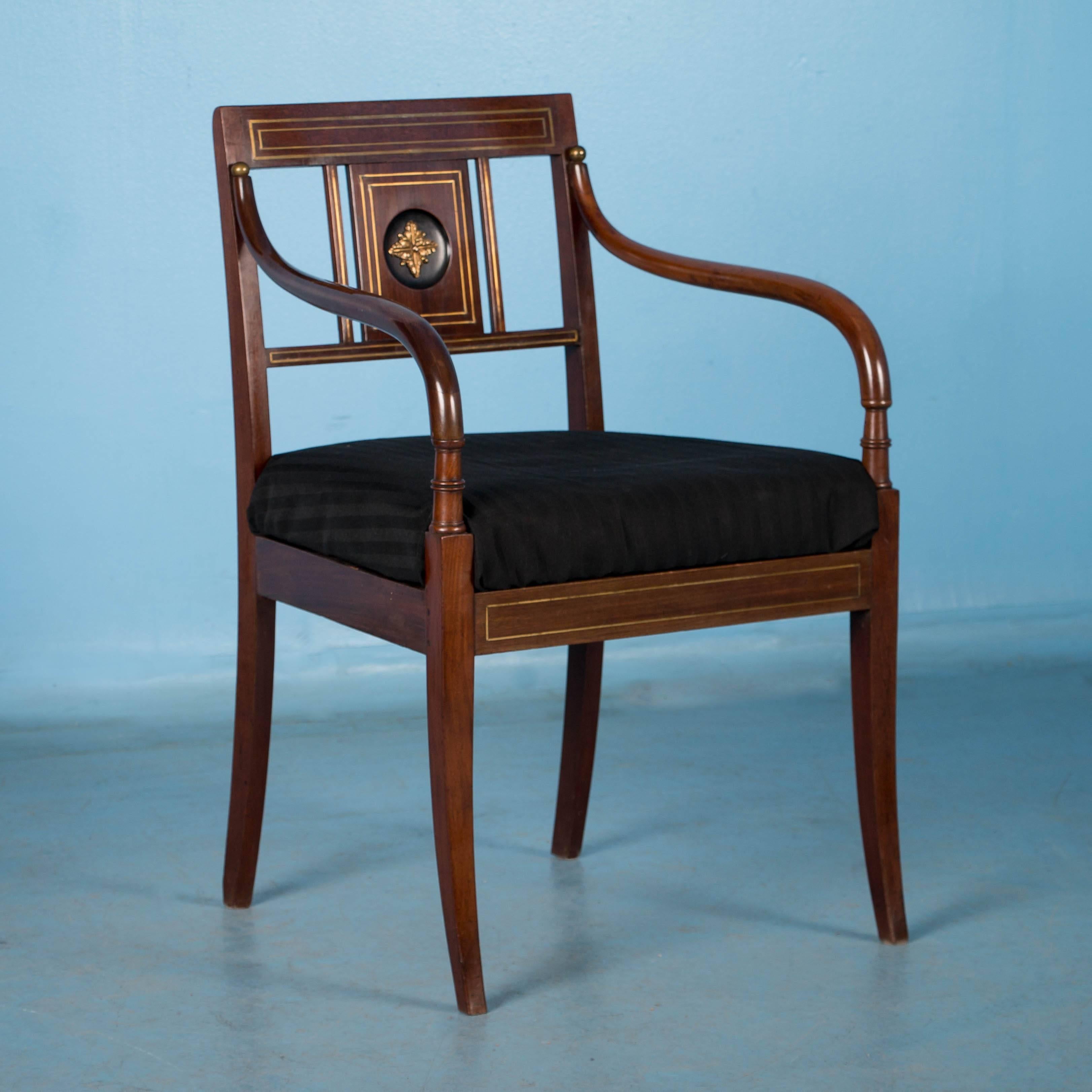 Refined and elegant, this exceptional pair of mahogany Empire period arm chairs are from Stockholm, Sweden. Note in the close up photos the brass inlay and medallion in the center panel of the back adding to the stately appeal of the pair. Both