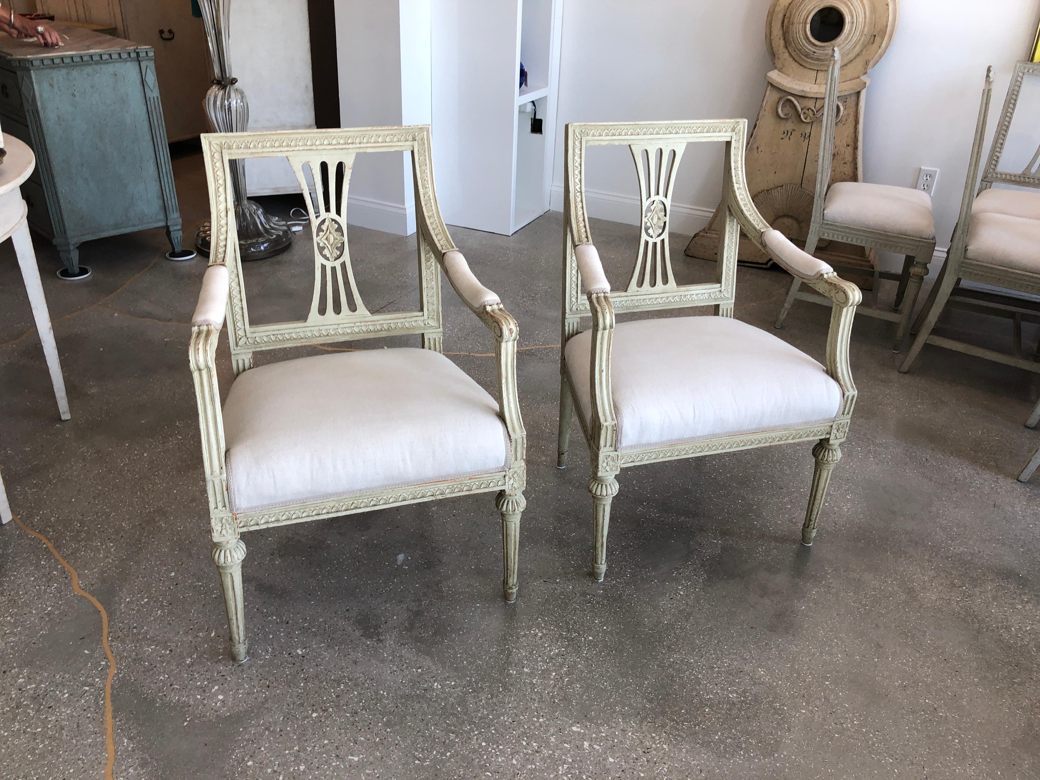 Pair of antique Swedish late Gustavian armchairs, painted in lovely greyish-green distressed finish. Squared backs with carved egg and dart border, graceful curved arms with an upholstered fabric pad. Openwork splat back with carved rosette in